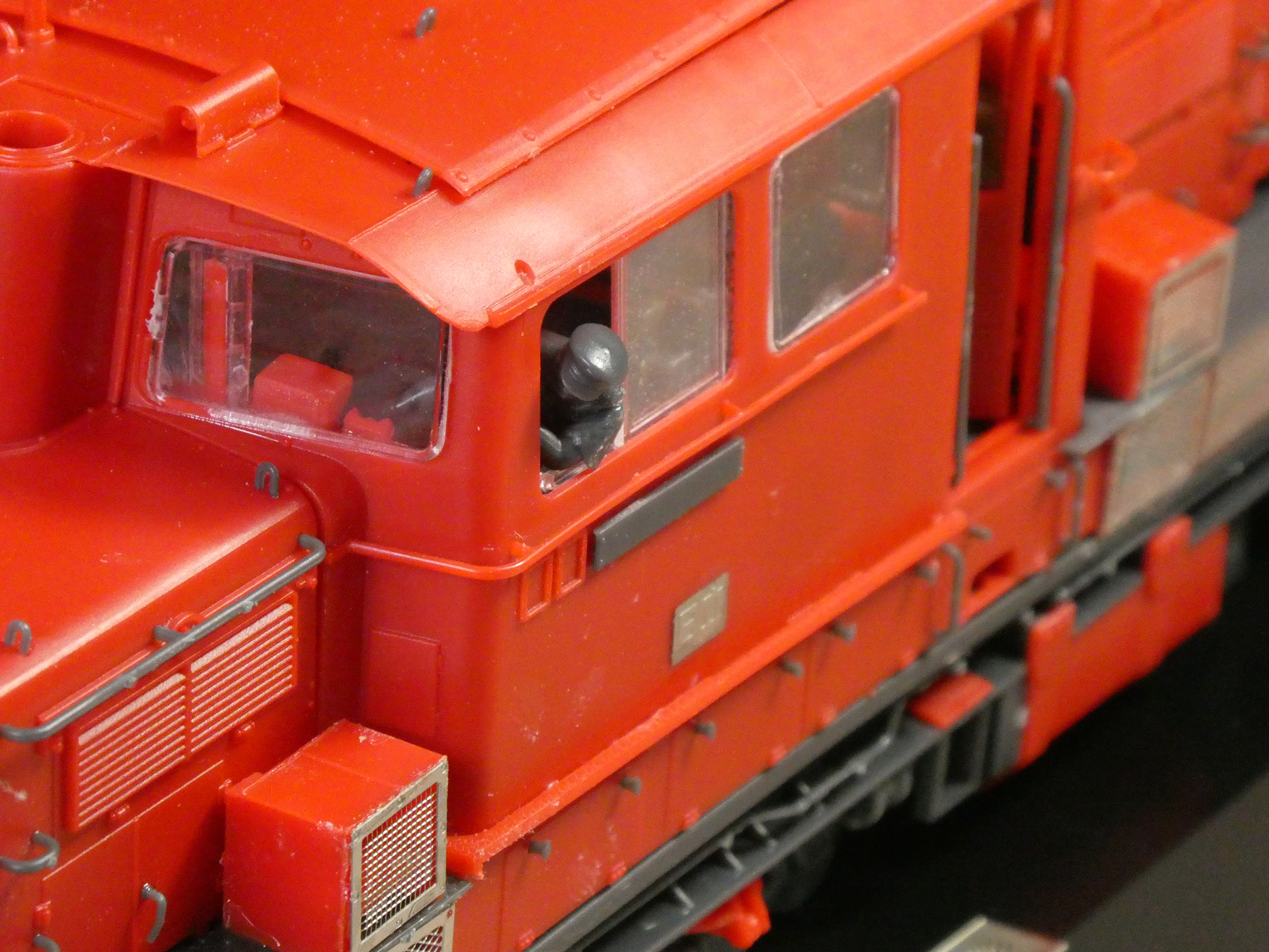 運転士の人形は「夏服」と「冬服」が一体ずつある。こちらは「夏服」で、運転席の窓から肘を出すポーズ。運転席窓のこの部分は透明パーツの引き戸で開閉可能。運転室扉、バッテリー室の蓋も開閉できる