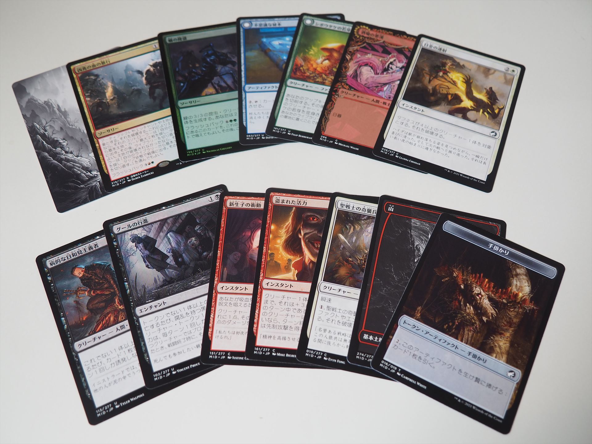 典型的な1パックの中身。左上がアートカードで、その右が両面または片面カード（レア/神話レア）、その右がフォイル確定枠（全レアリティ）、その右2枚が両面または片面カード（全レアリティ）、その右2枚が両面または片面カード（コモンまたはアンコモン）。左下から右2枚は片面カード（アンコモン確定）、その右3枚が片面カード（コモン確定）、その右が「永遠の夜」仕様フルアート版基本土地、一番右がトークンまたは広告カードまたは「ザ・リスト」（このパックでは「手掛かり」トークン）