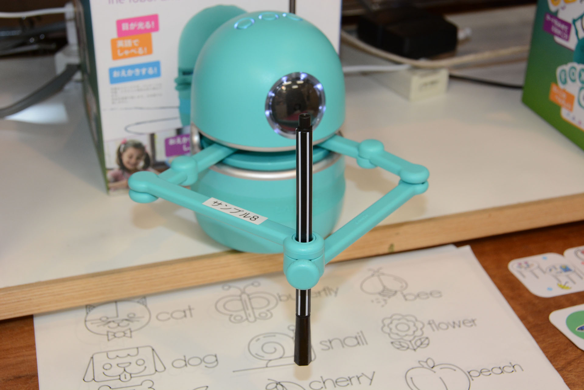 クインシーは2本のアームに固定されたペンでお絵かきができるロボット。中央の目のようなセンサーでQRコードを読み込ませる
