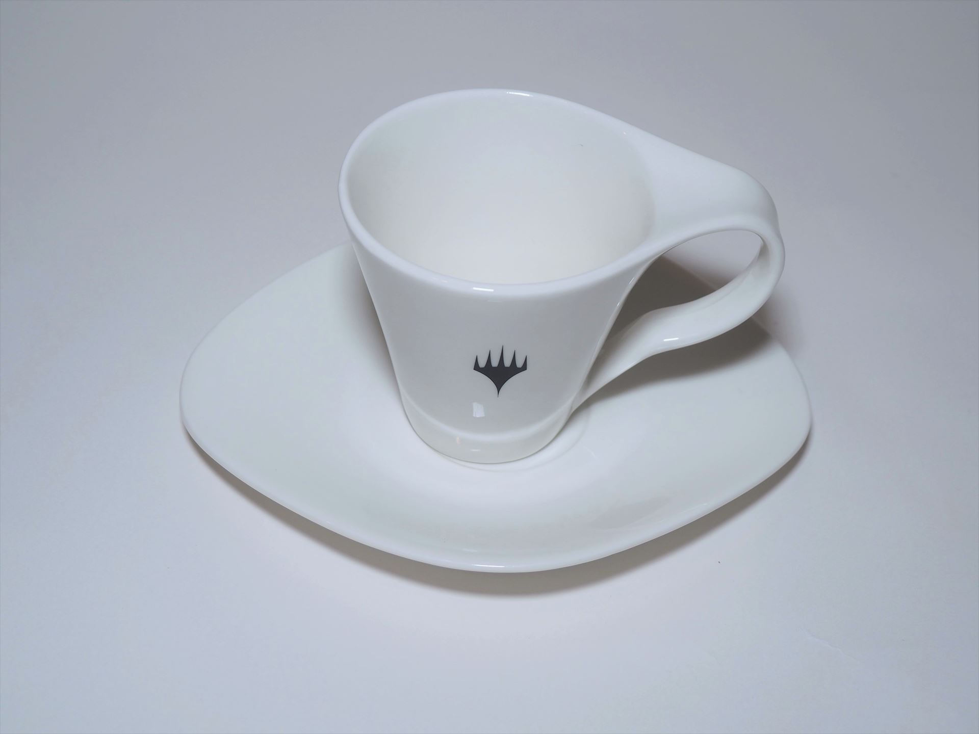 ティーカップとソーサー。ティーカップには次元を自由に行き来できるプレインズウォーカーを表すシンボルが描かれている