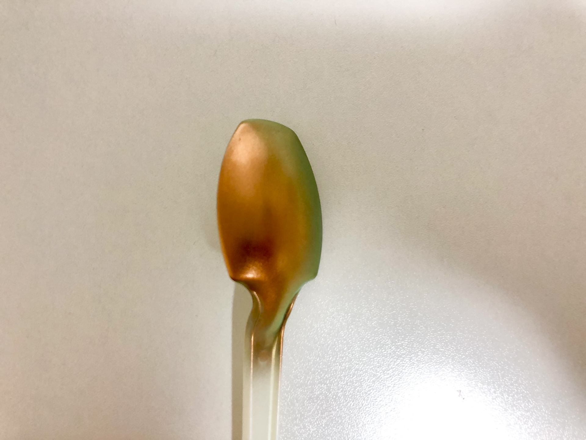 ガイアノーツの偏光塗料「プリズムメタリックオレンジライトグリーン」をスプーンに塗装したサンプル。ゴールドがグリーンに変色していることがわかります。