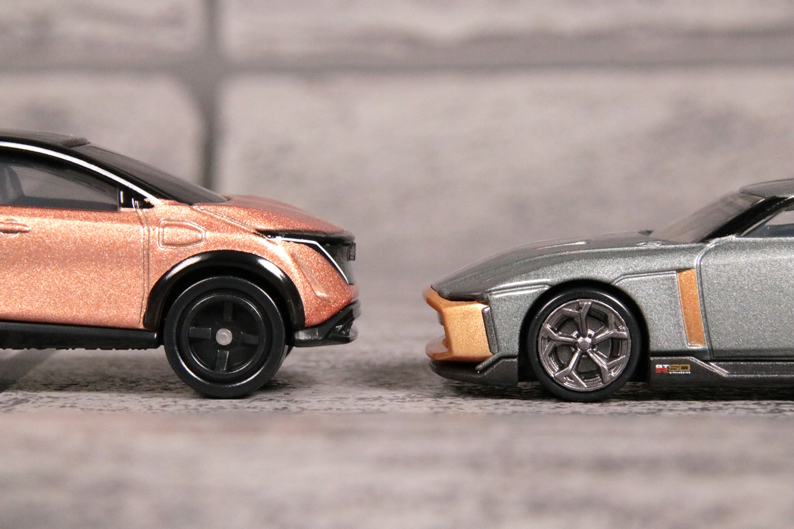 左がトミカ「No.64 日産 アリア」、右がトミカプレミアム「23 日産 GT-R50 by イタルデザイン」。両シリーズとも実車の再現度が高いが、トミカプレミアムシリーズでは汎用ホイールではなく、クルマ個々のデザインを再現した専用ホイールが採用されているのが大きな特徴だ