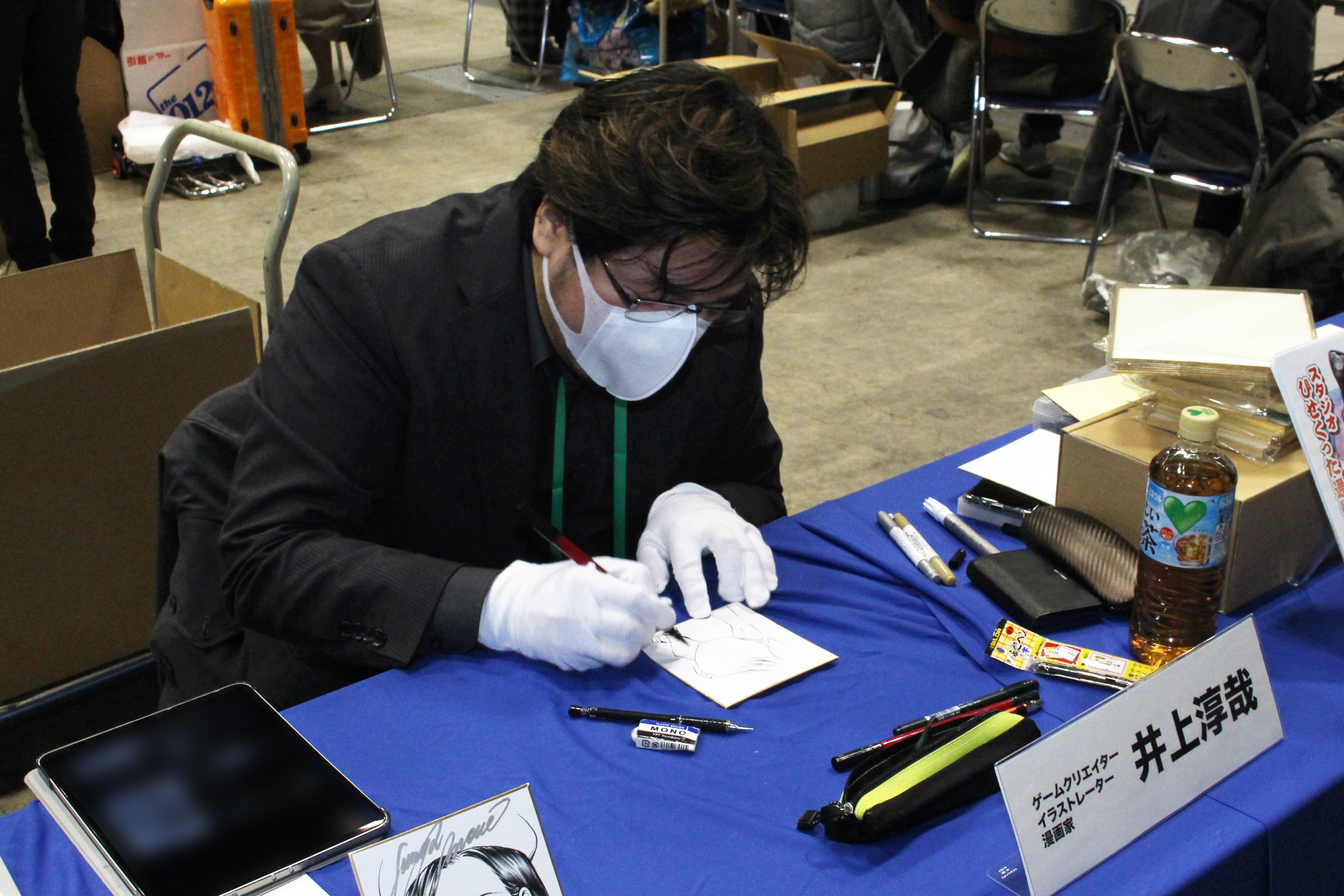 ミニ色紙にイラストとサインを入れる井上淳哉氏