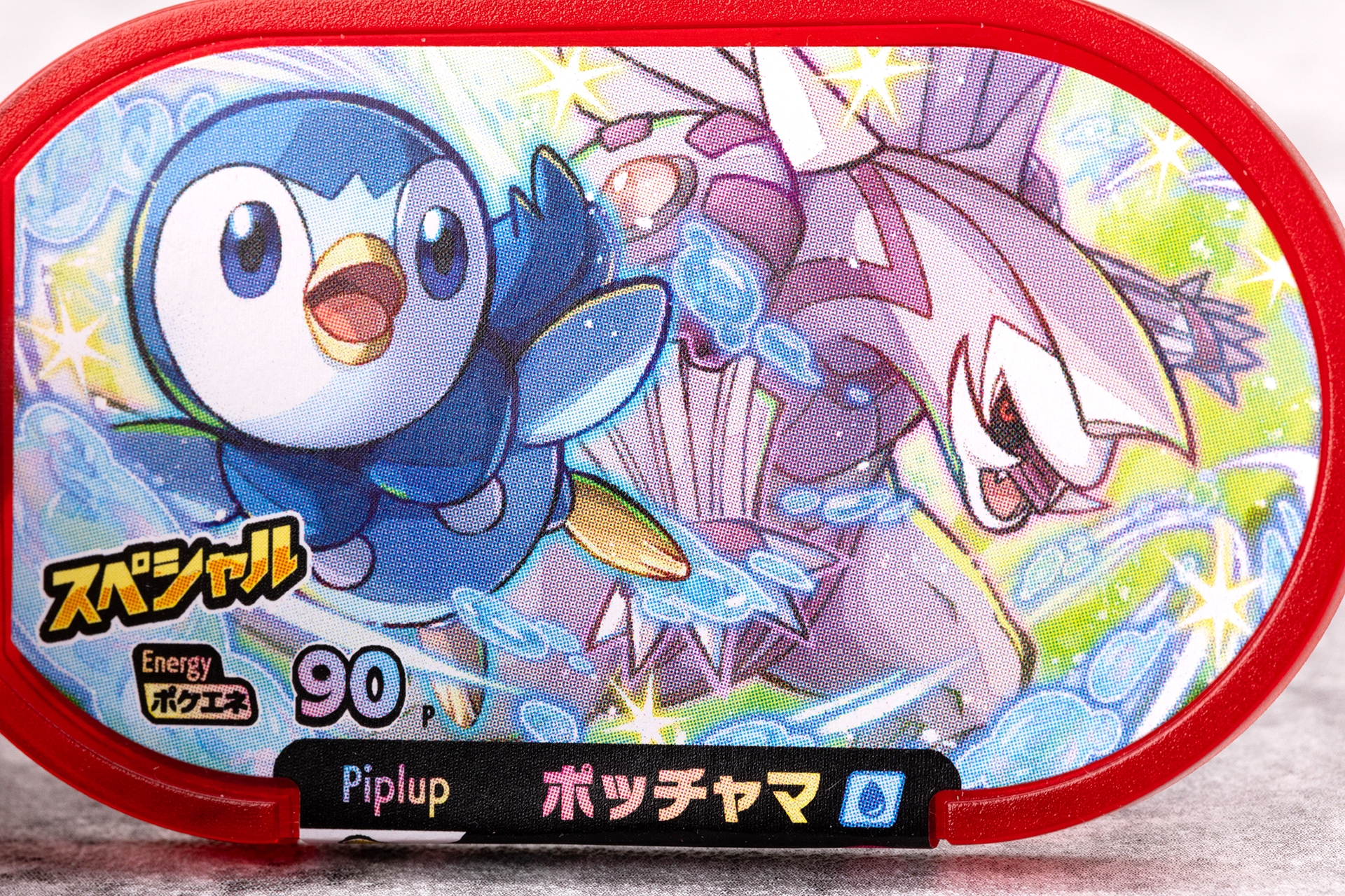 表面の黒地の部分には、ポッチャマの名前と英語表記のPiplup、みずタイプを表わすアイコンが記載されている