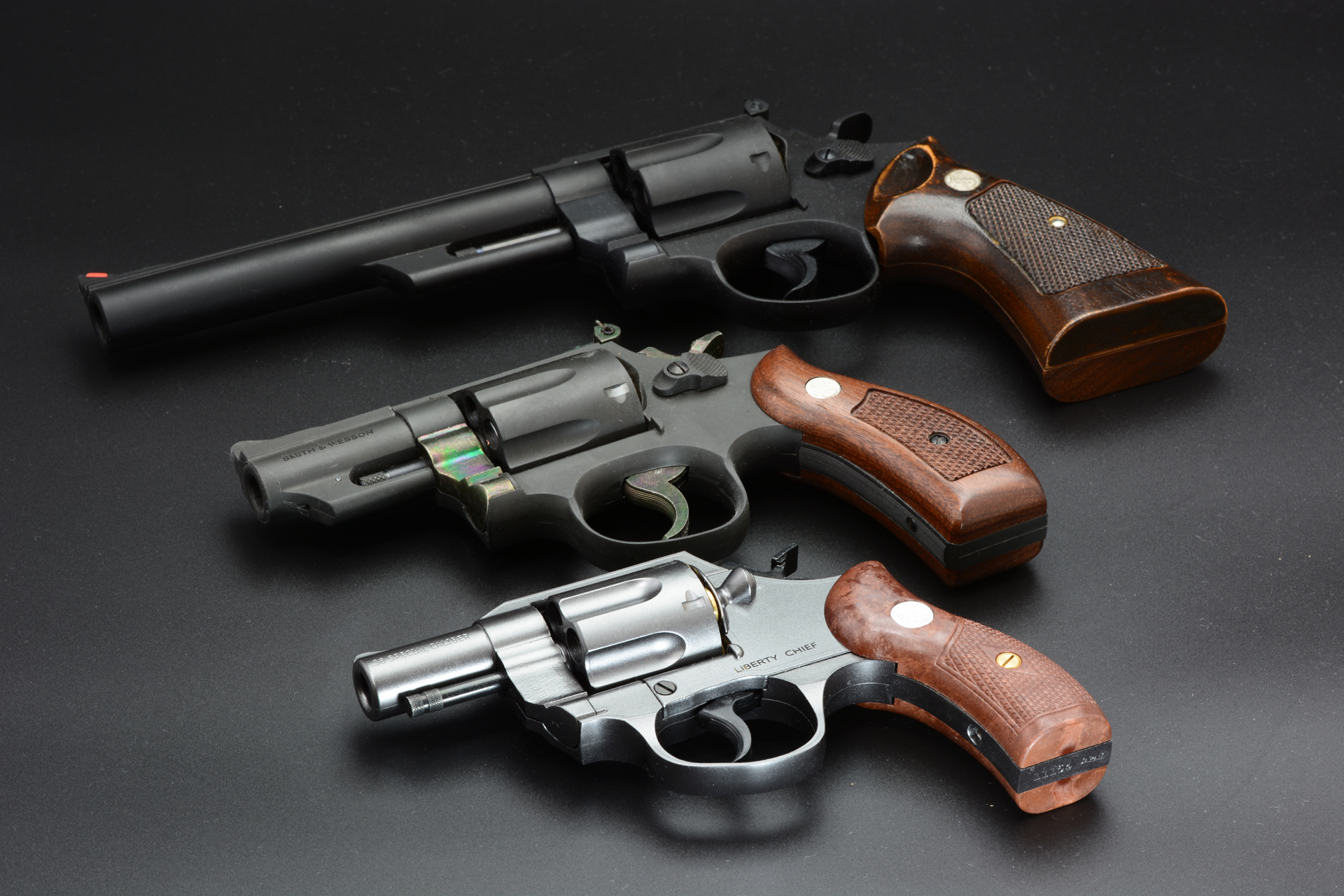 筆者のモデルガンコレクションと並べてみた。上の大型拳銃はタナカの「S&W M29」、中央の中型拳銃はハートフォードの「S&W M19」。比べると「LIBERTY CHIEF .38special 2インチモデル」の小ささがわかる
