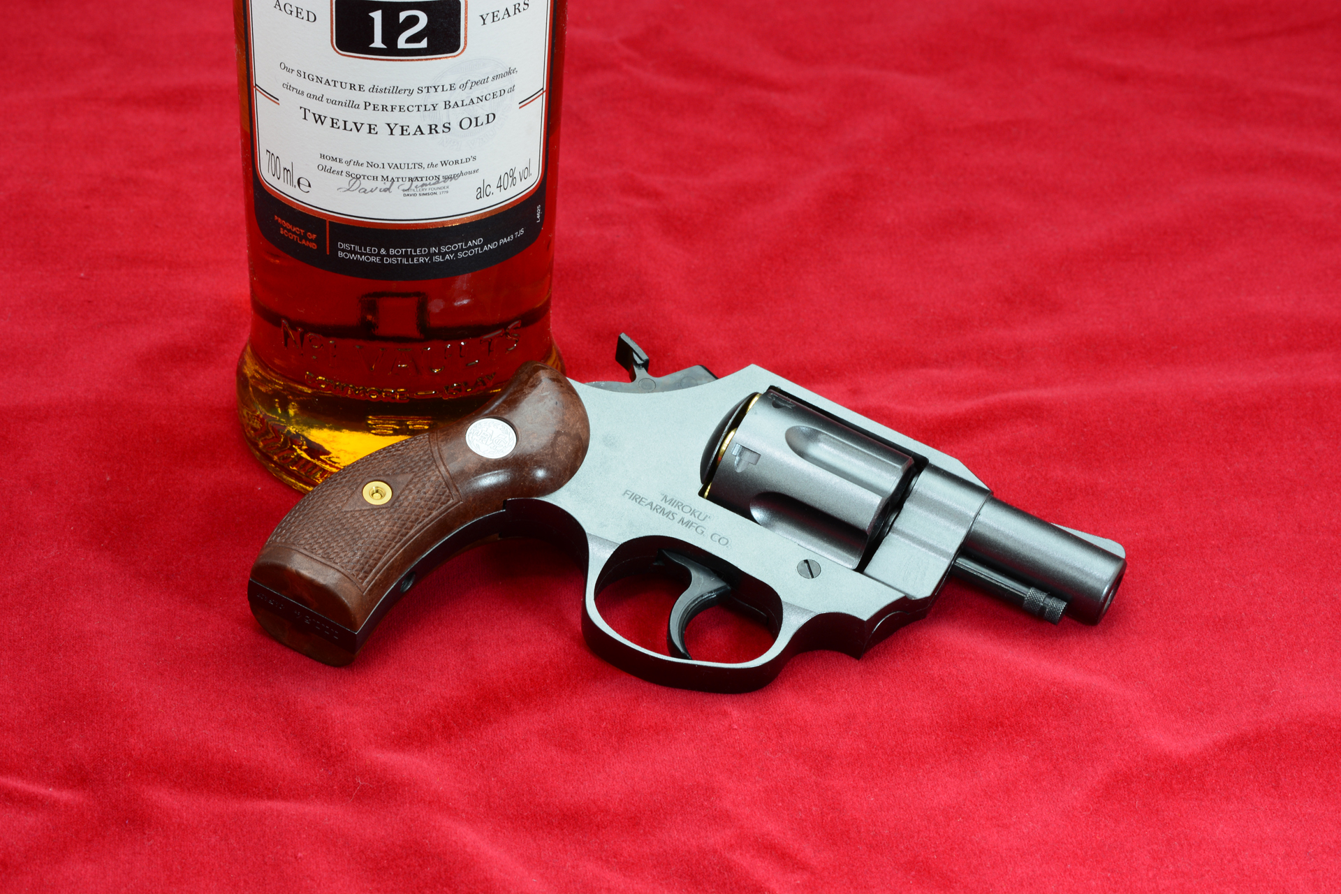鮮やかな赤の生地。筆者の好きなスコッチウィスキーの瓶も置いてみた。リバティチーフはアメリカで売られた銃なので、本当はバーボンが良いかもしれない