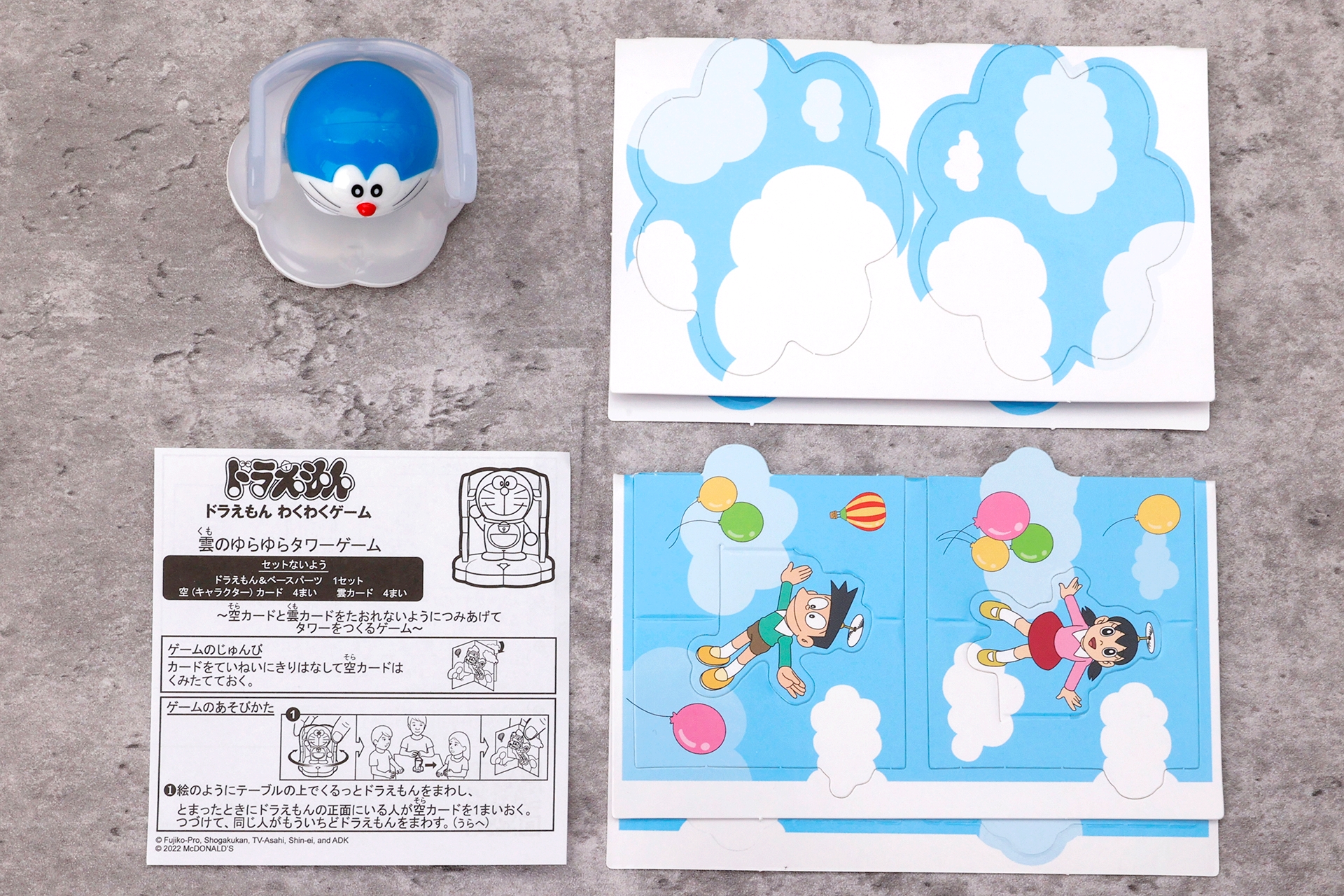 こちらが「雲のゆらゆらタワーゲーム」のおもちゃ袋の中身。ドラえもん＆ベースパーツが1セット、空カードと雲カードが各4枚、そして説明書となっている