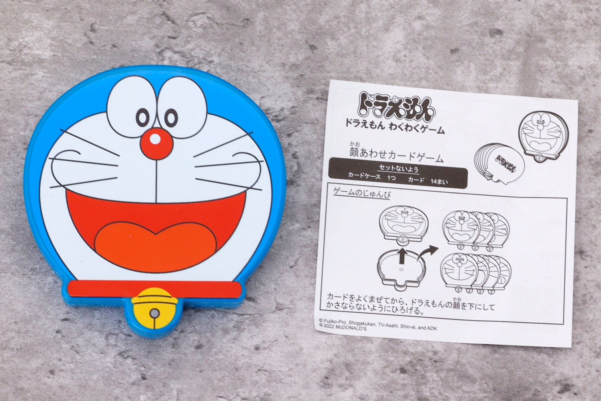 「顔あわせカードゲーム」のおもちゃ袋の中身は、ドラえもんの絵が描かれたカードケースと14枚のカード、説明書だ