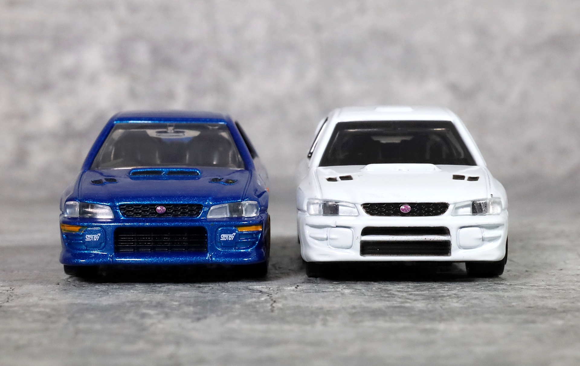 左がトミカプレミアム「30 スバル インプレッサ WRX タイプR STi バージョン」、右がトミカ「SUBARU インプレッサ WRXtypeRA STi Version V」（トミカギフトセット「スポーツカーヒストリーコレクション」に収録）