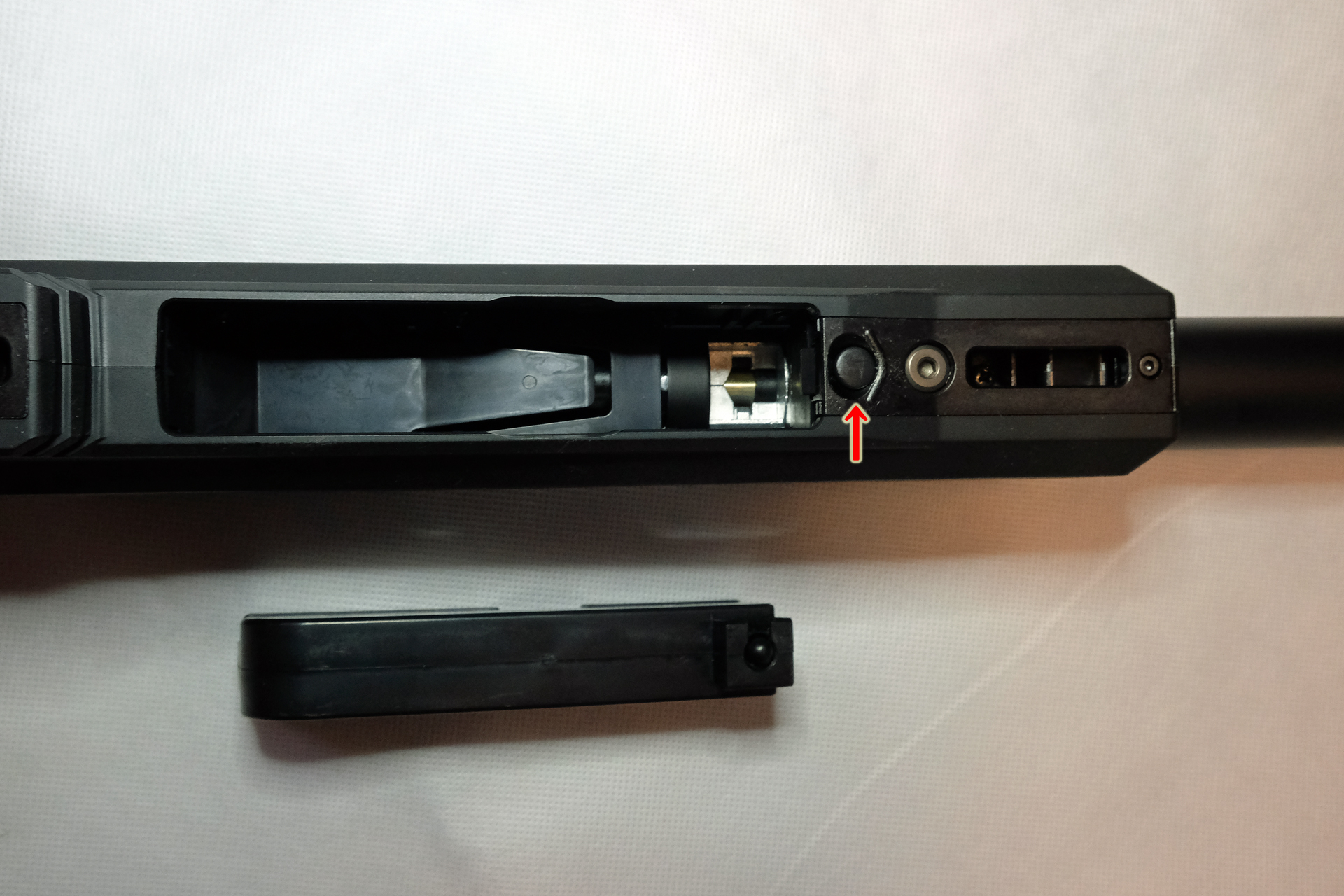 マガジンを外すと板バネが見える。矢印がロックボタン