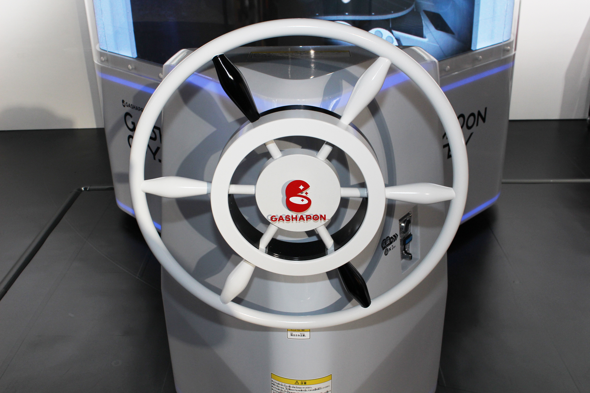 操舵輪のようなハンドル。左右の回転と押し込み操作ができる。向かって右側にコイン投入口がある