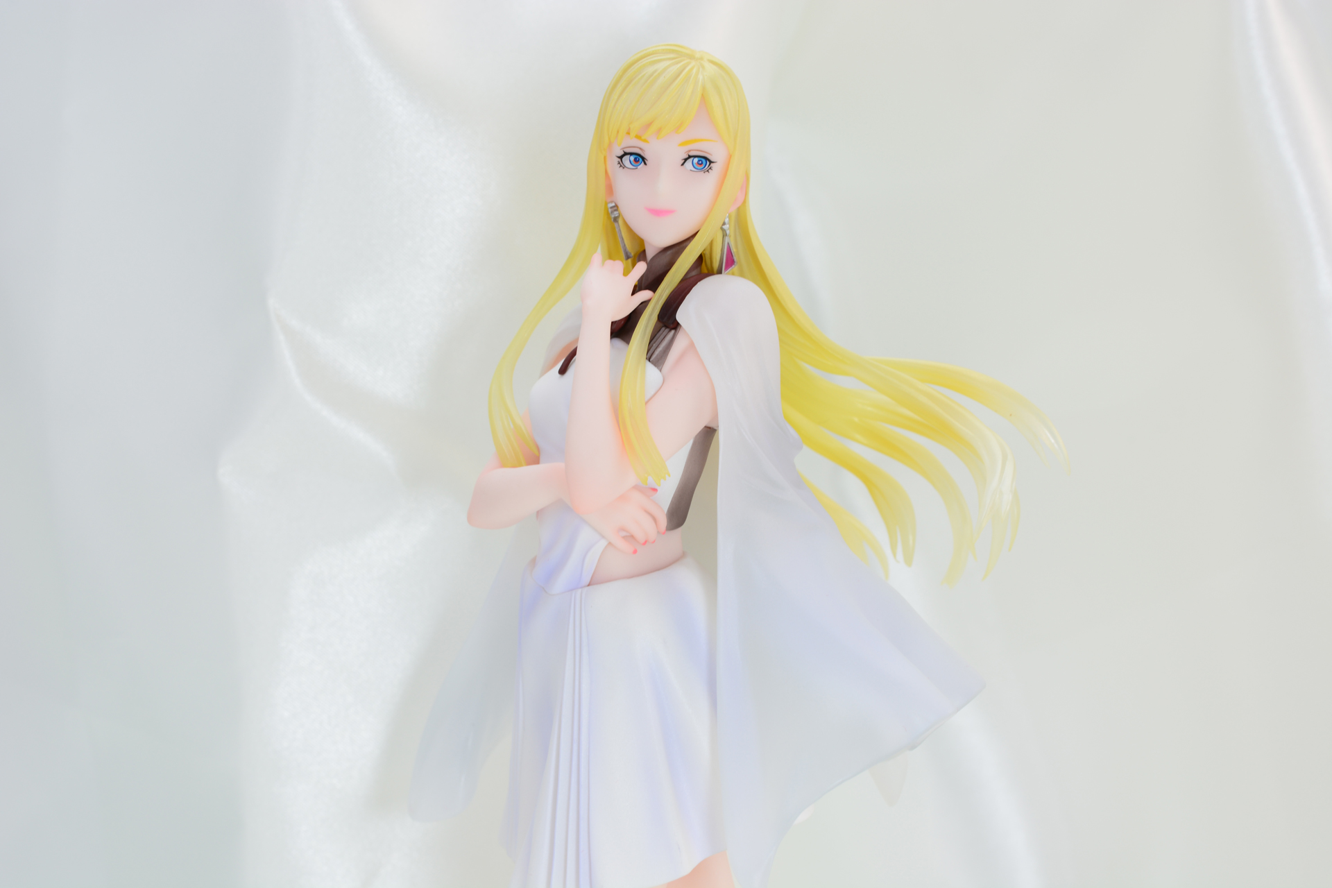 白い光沢のある布の背景は、溶け込んでしまうことなく、ギギの金髪を引き立てる