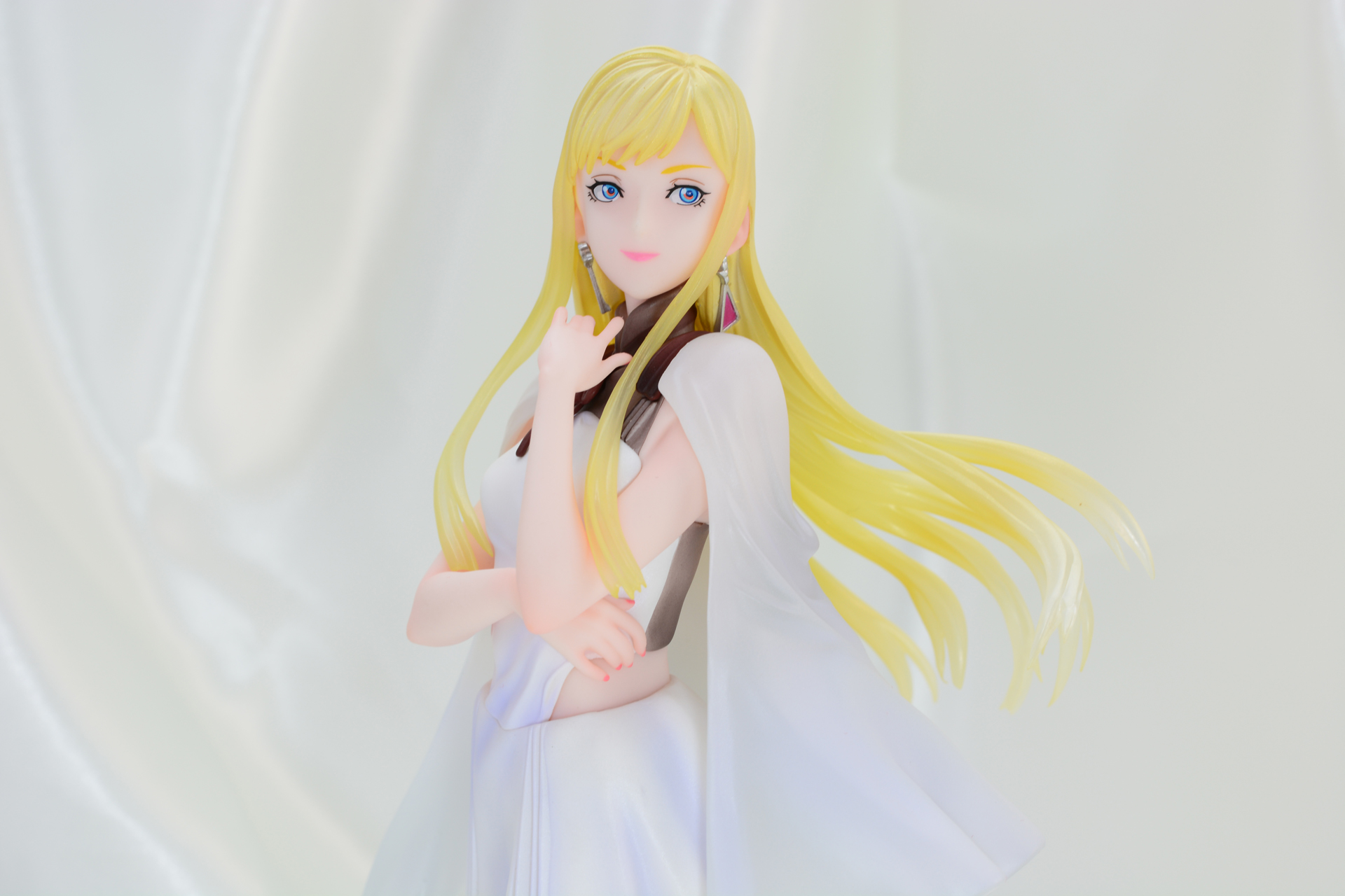 白い光沢のある布の背景は、溶け込んでしまうことなく、ギギの金髪を引き立てる