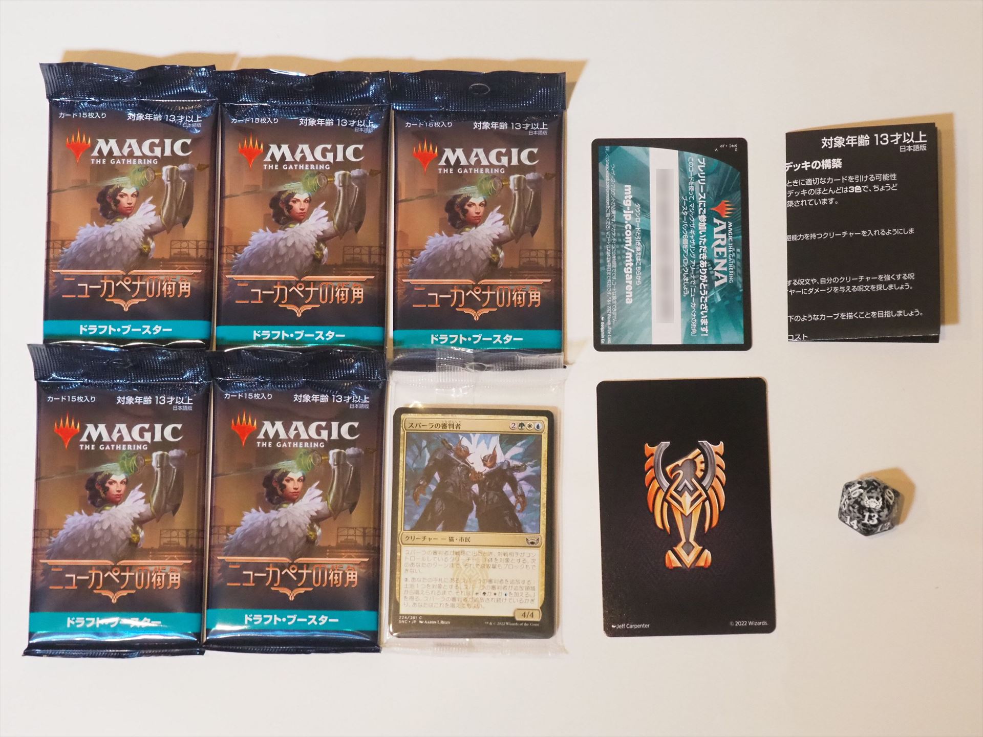 斡旋屋一家の箱の中身。ドラフト・ブースターが5パックと、透明な袋に入ったファミリー・ブースター（選んだ一家に合う色のカードが15枚入っている）、スピンダウン・カウンター、MTGアリーナのコード・カード、デッキ構築ガイド、デッキセパレーターが入っている