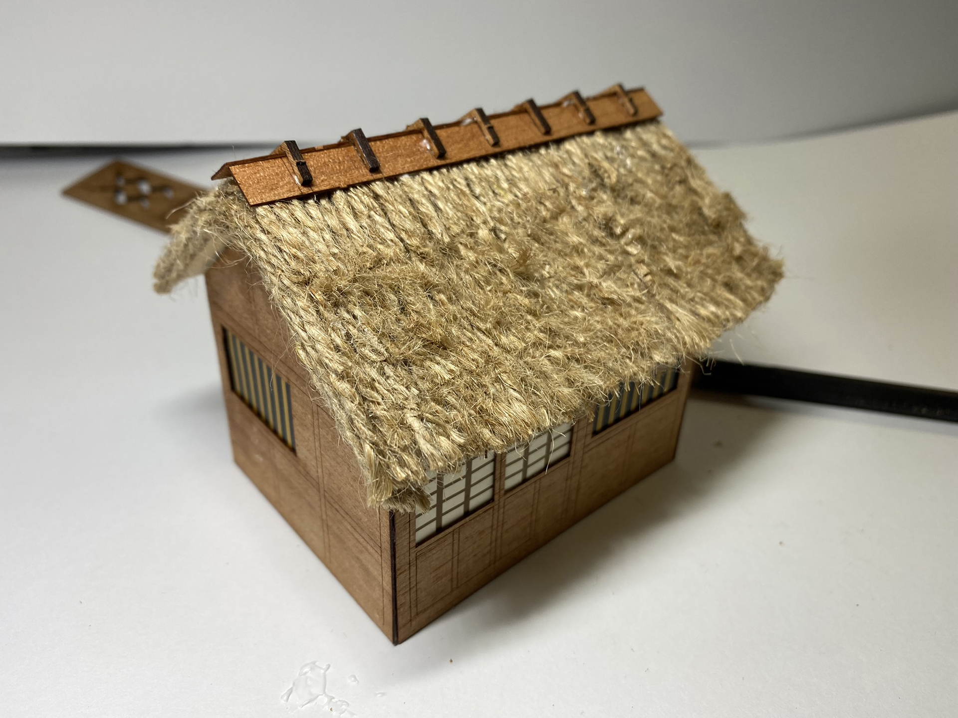 屋根のてっぺんに棟を取り付ける麻糸をかやぶき屋根に見えるように切り込みを入れ、ヤスリでほぐすのだが、うまくいったとはいいがたい感じだ。それでも独特の質感は出たと思う