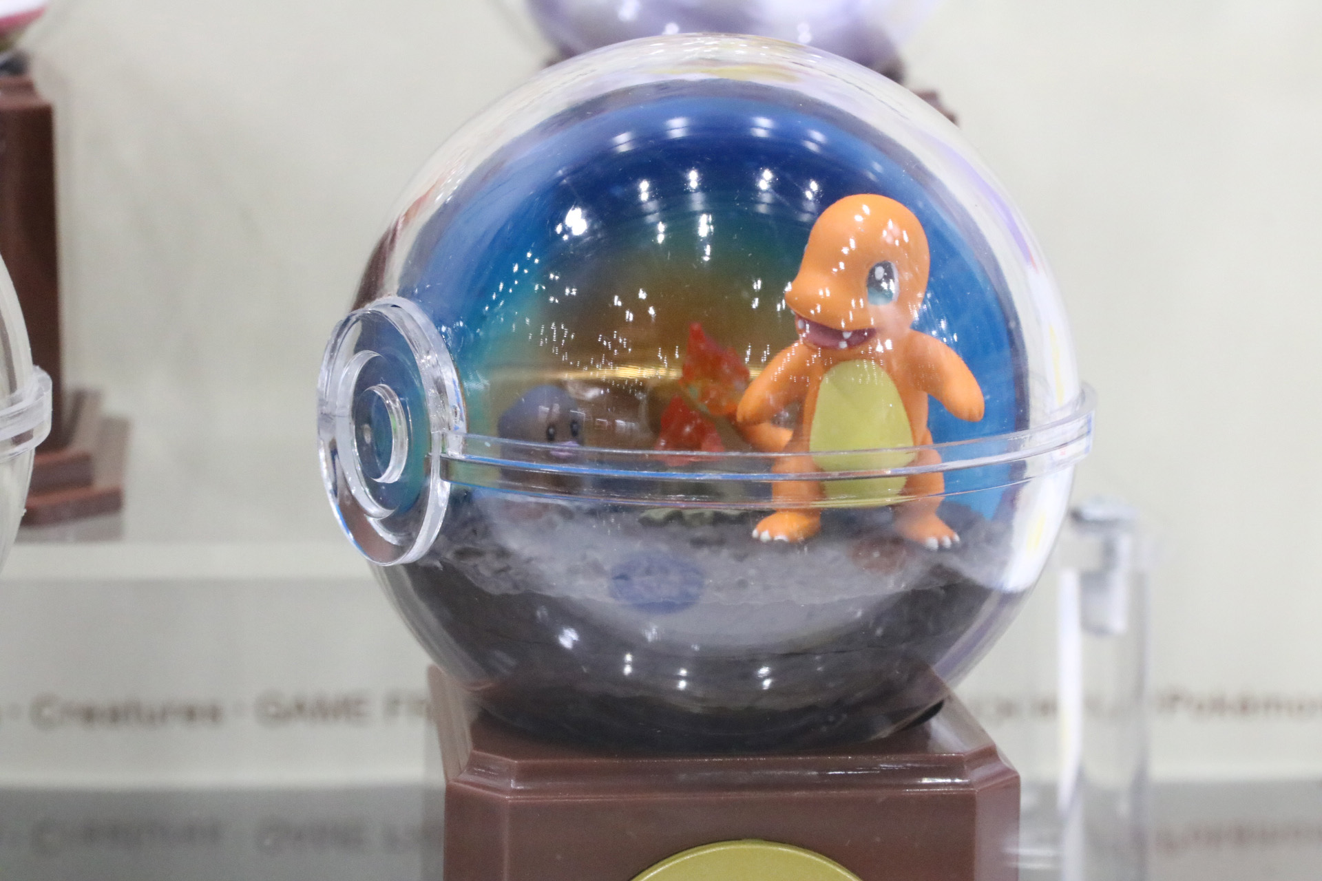 モンスターボール型の容器の中で小さなジオラマが表現されてる
