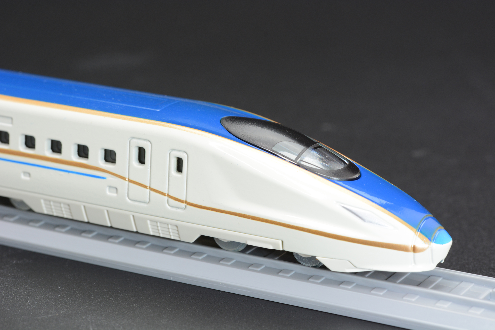 北陸新幹線 E7系は、JR東日本、JR西日本で運行される新幹線。工業デザイナーの奥山清行氏がデザインを担当、中央の青いラインとそれを縁取る金色のラインが印象的だ。キャノピー型の運転台やロゴマークもしっかり再現している
