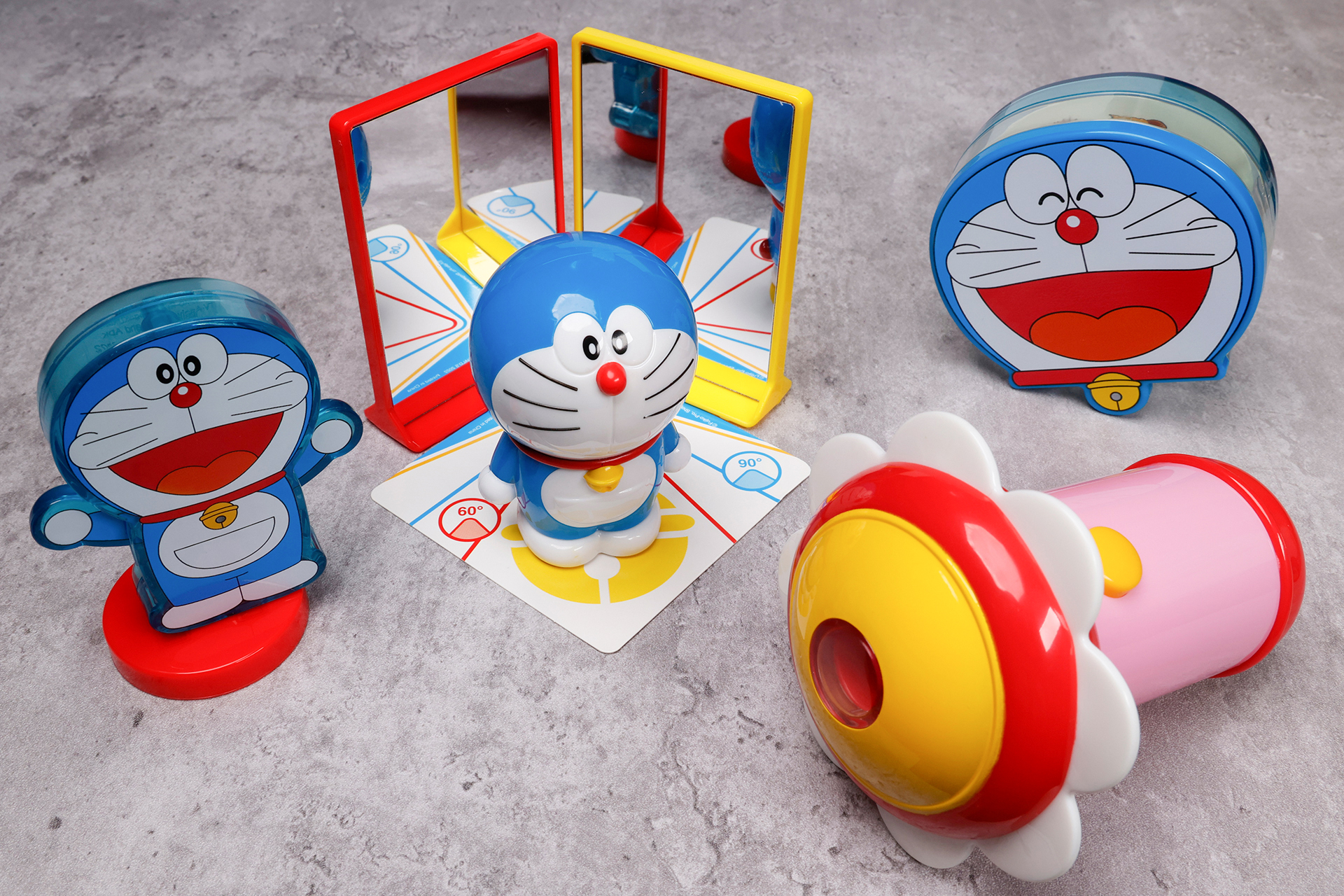 こちらが第2弾（8月12日～8月18日）のハッピーセット「ドラえもん わくわくじゆう研究」に登場するおもちゃ。写真左から「見つけてみよう！金属たんちき」、「どう映るかな？かがみの実験」写真右奥が「じっくり研究！観察ボックス」で写真手前が「のぞいてみよう！ドラミのスモールライト」