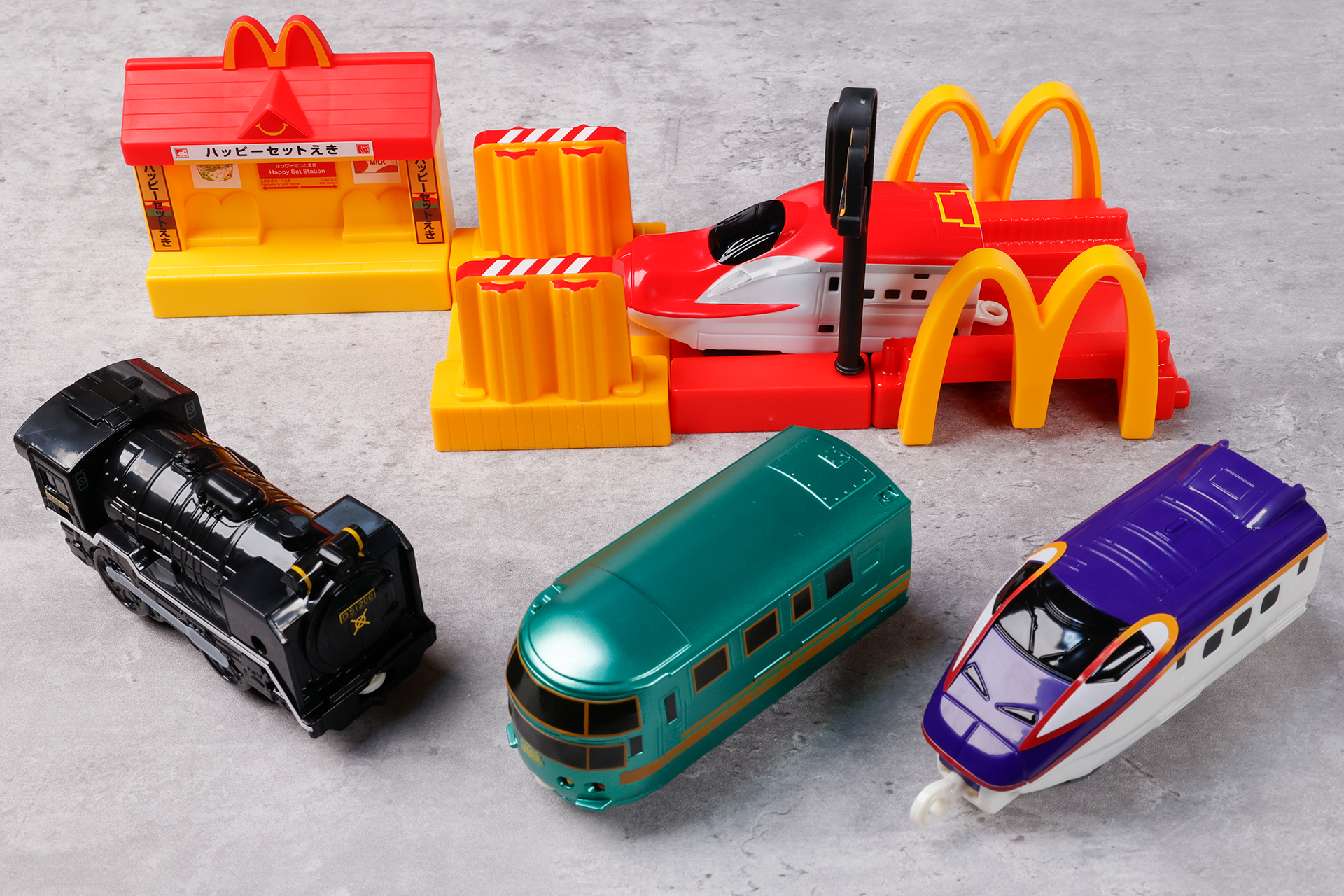こちらが第2弾（10月14日～10月27日）のハッピーセット「プラレール」に登場するおもちゃ。写真上が「E6系新幹線こまち＆マクドナルド橋」、写真左下から「D51 200号機蒸気機関車＆マクドナルド信号」、「JR九州ゆふいんの森＆ハッピーセットえき」、「E3系新幹線つばさ2000番代＆マクドナルド洗車場」