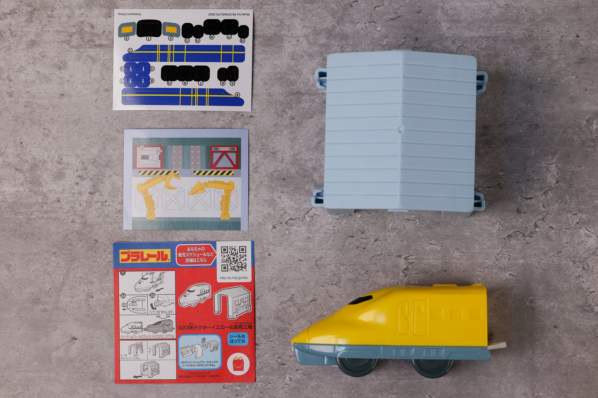 こちらがおもちゃ袋の中身。シールのほか、車両工場に取り付けるためのカードも付属している