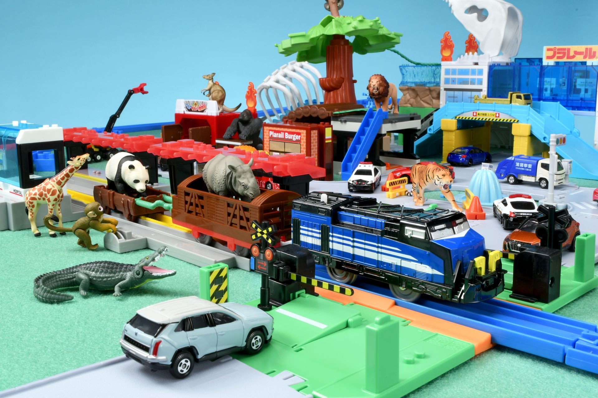 サイとジャイアントパンダを乗せた列車が通過するのを待つ車とワニ。列車を止めるレバーを操作しているのは……