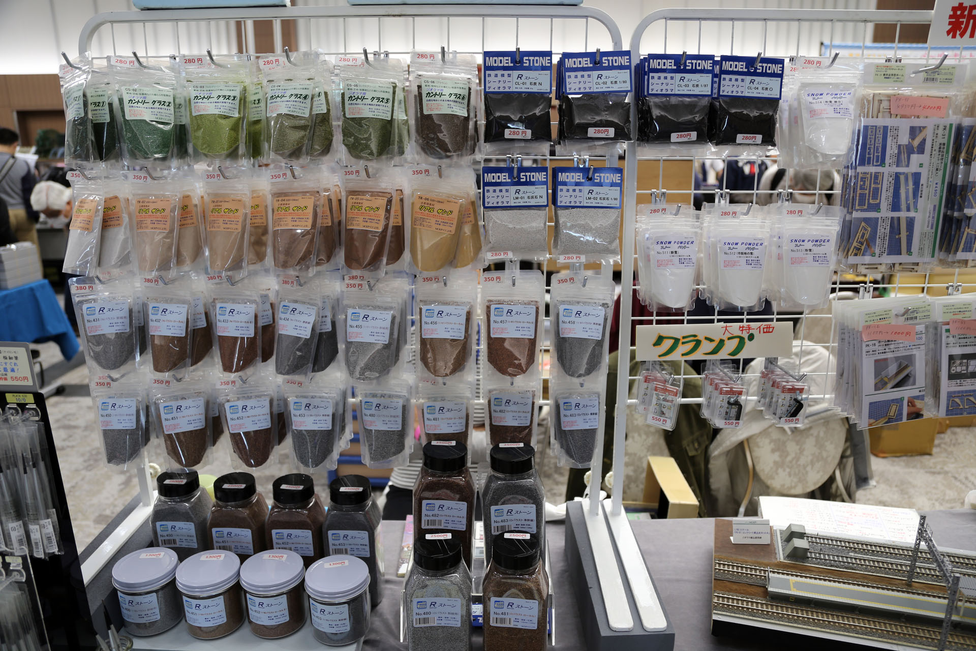 こちらは「粉物」専門店のモーリン。ジオラマに欠かせない砂利や草を表現する緑の粉など。線路に敷く砂利「バラスト」は濃い茶色、茶色、灰色の3色あって、古い線路は濃い茶色、交換したばかりの線路は灰色などと使い分ける。「雪」は大理石を削って作るという。ある程度重くないとジオラマに定着しないそうだ。