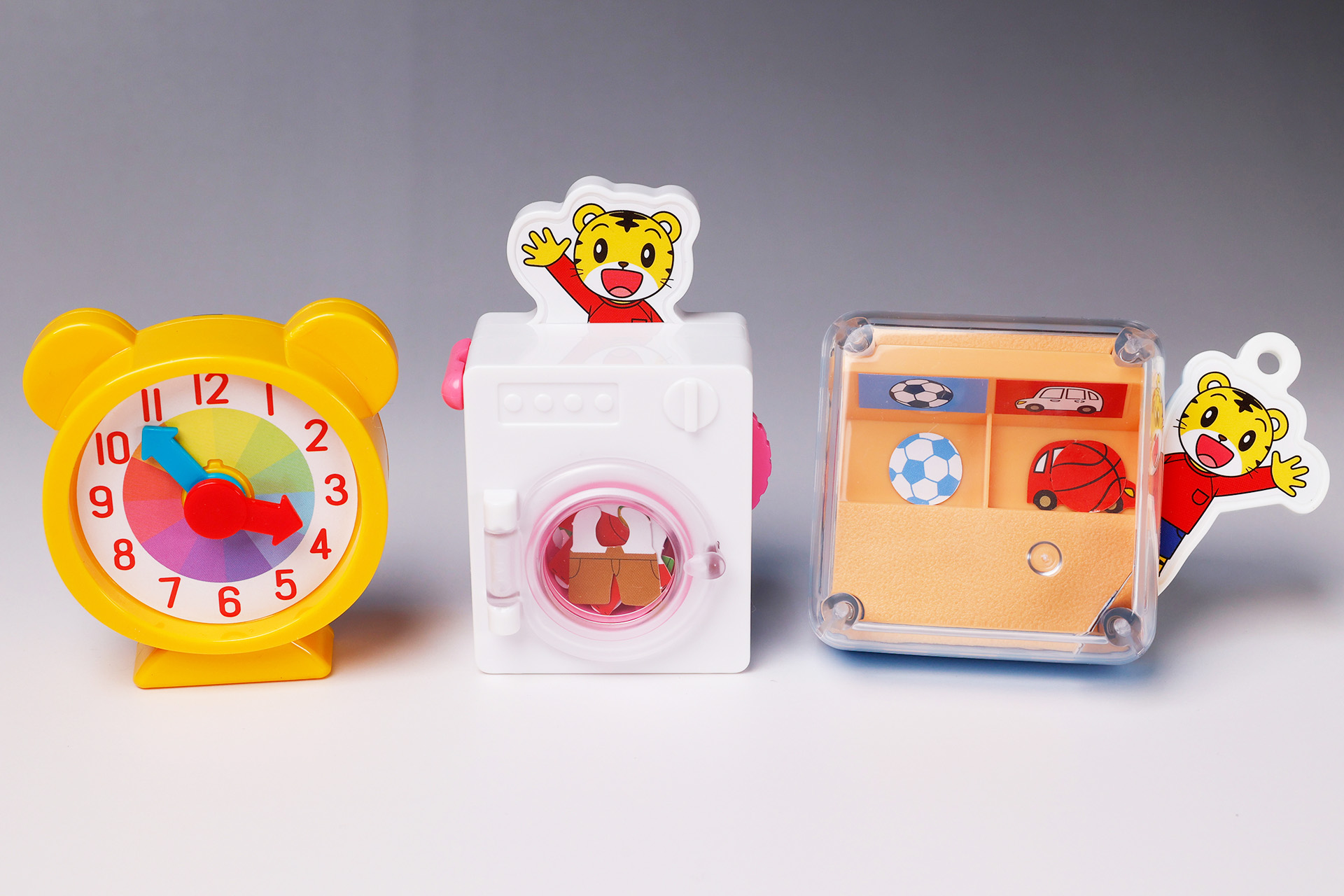 こちらが第1弾（11月4日～11月10日）のハッピーセット「しまじろう」に登場するおもちゃ。写真左から「いま なんじ？しまじろうの とけい」、「しまじろうとクルクル おせんたく」、「しまじろうとおかたづけゲーム」