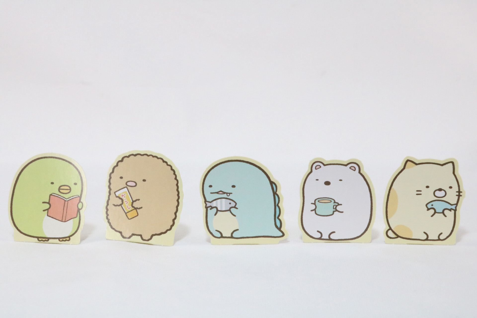 左からとかげ、とんかつ、とかげ、しろくま、ねこ。本を読んだり、ご飯を食べたりするすみっコたちが表現されている