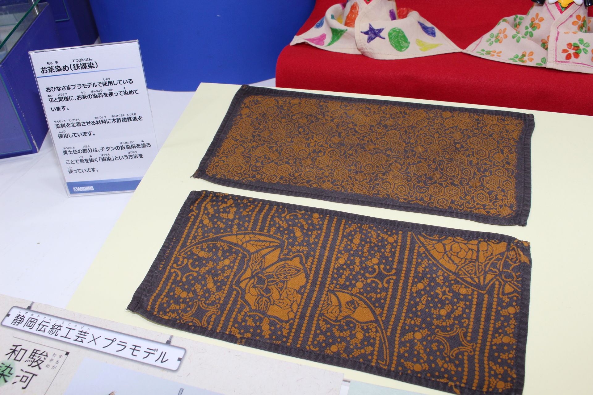 着物と同じ布を「お茶染めの鉄媒染」という工法で染めたもの。染料の定着に木酢酸鉄液を使用し、チタンの抜染剤を塗って抜染した部分が黄土色になっている