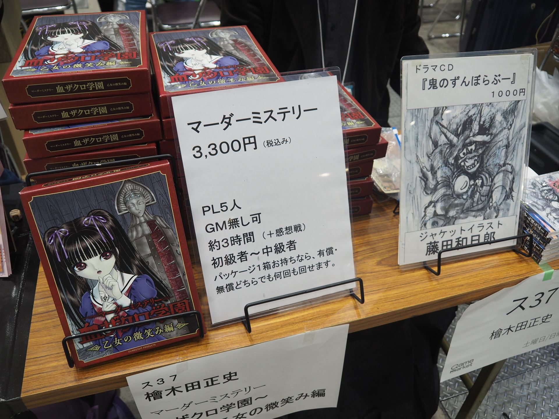 檜木田正史のブースでは、マーダーミステリー「～血ザクロ学園～　乙女の微笑み編」とドラマCD「鬼のずんぼらぶー」が展示・販売されていた