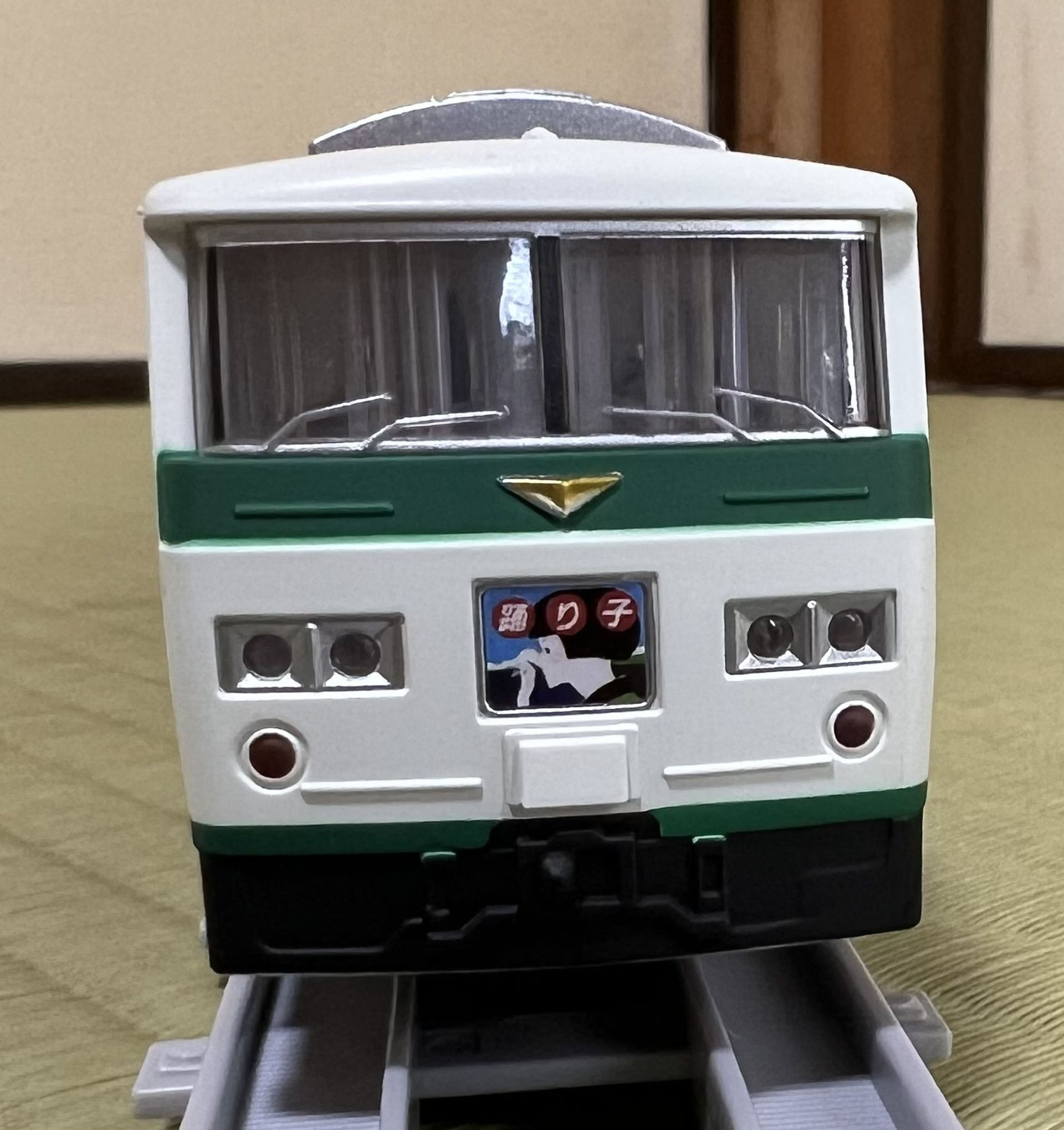 1両目の顔。逆三角形の特急エンブレム、ヘッドマーク、4灯ヘッドランプが実物にそっくりだ。連結器の上の部分は、実車では緑のストライプがつながっている。プラレール リアルクラスでは、この部分がシャーシ側パーツとなっているため黒い。緑色を足そう。鉄道模型用の塗料で「緑14号」が該当する。