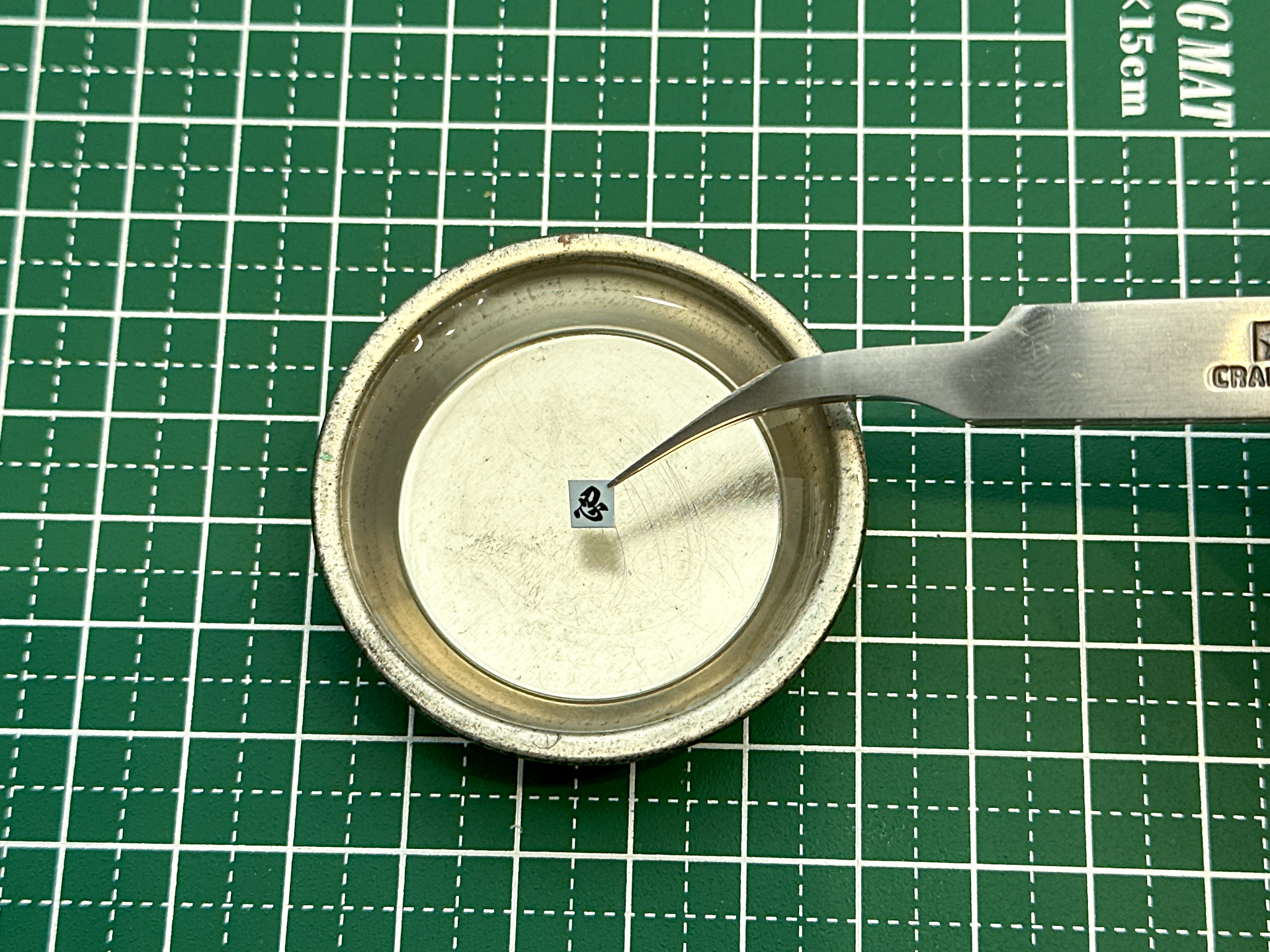 切り出したデカールを水に浸します。ピンセットを使うことで作業性がアップします。