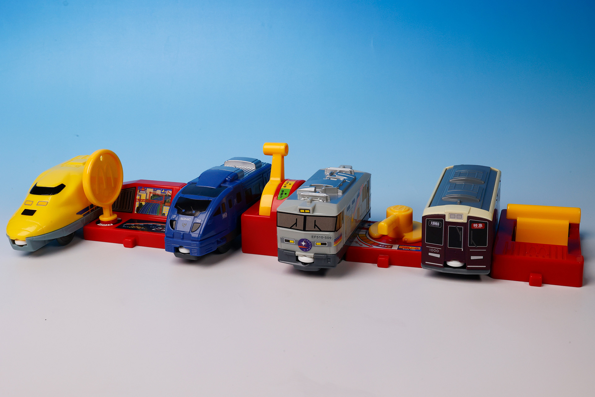 こちらが第2弾（9月29日～10月12日）のハッピーセット「プラレール」に登場するおもちゃ。写真左から「923形ドクターイエロー＆運転台」、「JR 九州 883 系ソニック＆走行レバー」、「寝台特急カシオペア＆ブレーキレバー」、「阪急電鉄 1000 系＆前後きりかえレバー」
