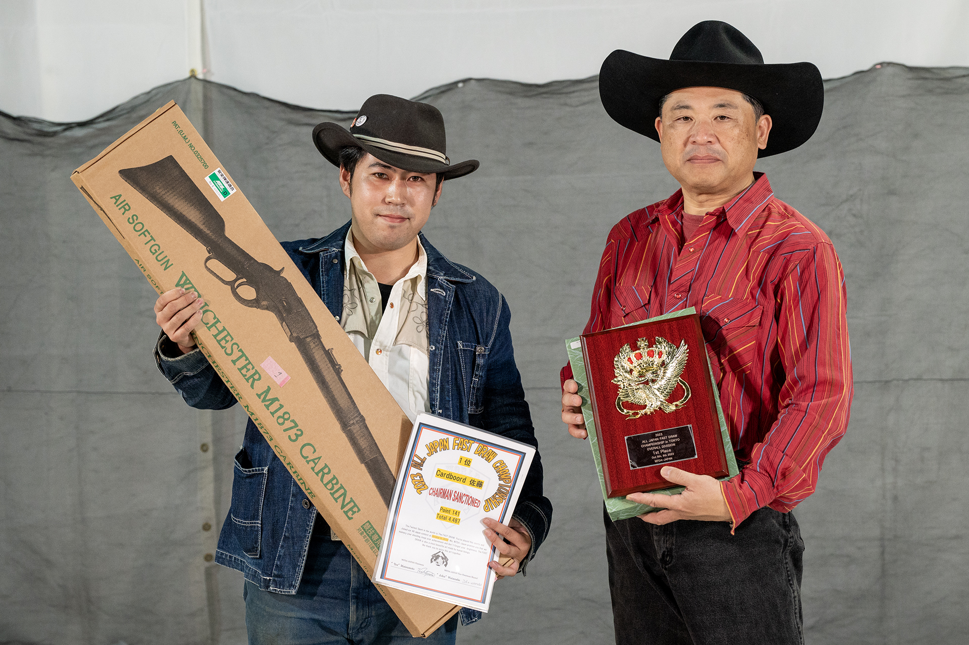 優勝者のCardboord 佐藤氏(左)。佐藤氏には、KTWのウィンチェスターM1873など副賞も贈られた。なお、協賛各社のご厚意により48位まで全員になにかしらの景品が提供された