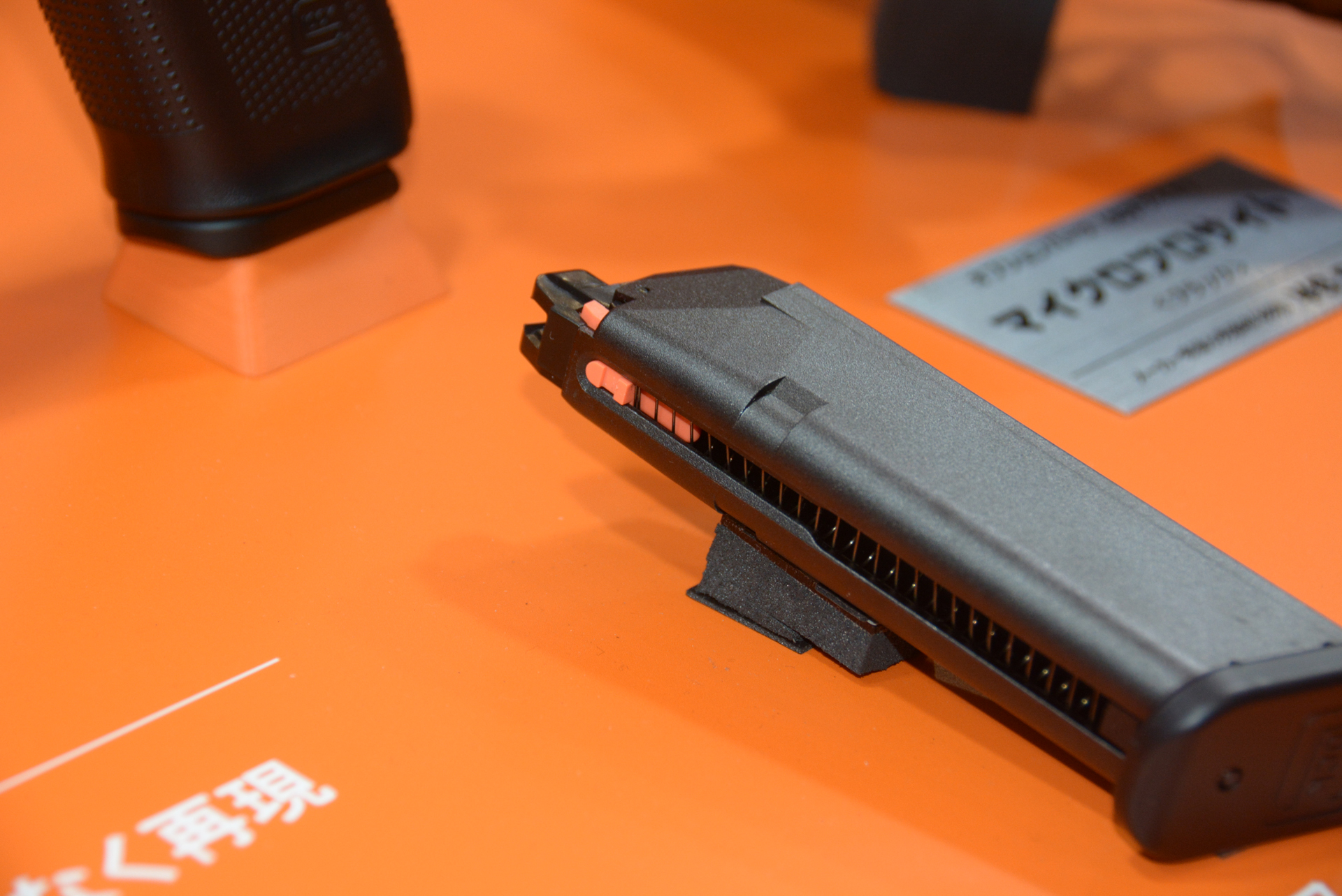 全日本模型ホビーショーでの注目商品。展示台のオレンジは、実銃の弾倉などに使われるオレンジの部品を意識してとのこと。製品でもマガジンの留め具などにオレンジを使用し、実銃の雰囲気を追求している