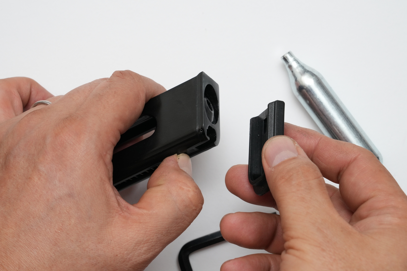 CO2 12gカートリッジを装着するためには、まずはマガジン前面下部のストッパーをずらして、マガジンボトムをスライドして取り外す。その後マガジン底部の円形ベースカバーを取り外してから、CO2 12gカートリッジを挿入する。最後にベースカバーを六角レンチで軽く締め込んで、接触する手応えを感じたら素早く締め込む。締めすぎるとガスケットを傷めてガス漏れの原因となるので要注意