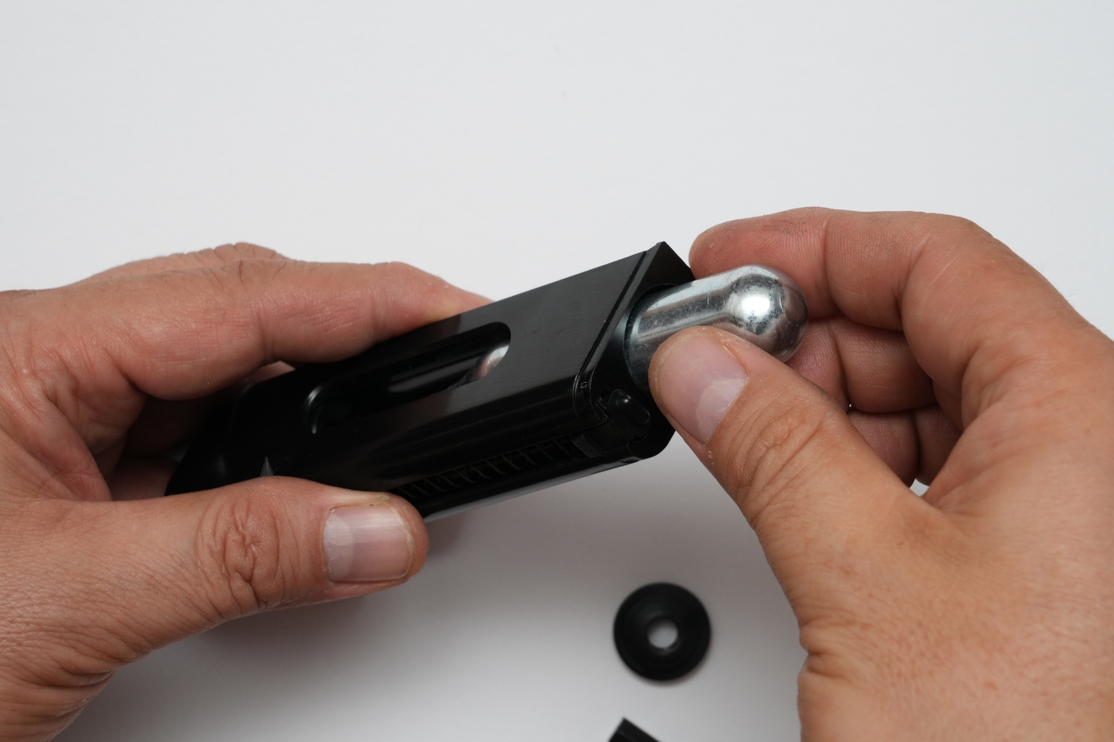 CO2 12gカートリッジを装着するためには、まずはマガジン前面下部のストッパーをずらして、マガジンボトムをスライドして取り外す。その後マガジン底部の円形ベースカバーを取り外してから、CO2 12gカートリッジを挿入する。最後にベースカバーを六角レンチで軽く締め込んで、接触する手応えを感じたら素早く締め込む。締めすぎるとガスケットを傷めてガス漏れの原因となるので要注意