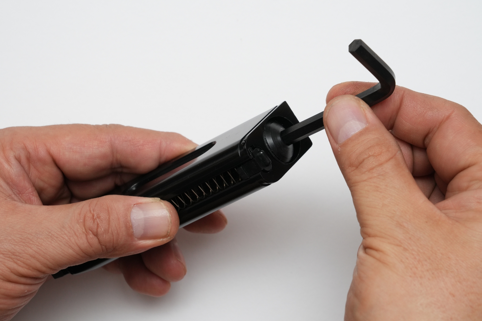 CO2 12gカートリッジを装着するためには、まずはマガジン前面下部のストッパーをずらして、マガジンボトムをスライドして取り外す。その後マガジン底部の円形ベースカバーを取り外してから、CO2 12gカートリッジを挿入する。最後にベースカバーを六角レンチで軽く締め込んで、接触する手応えを感じたら素早く締め込む。締めすぎるとガスケットを傷めてガス漏れの原因となるので要注意