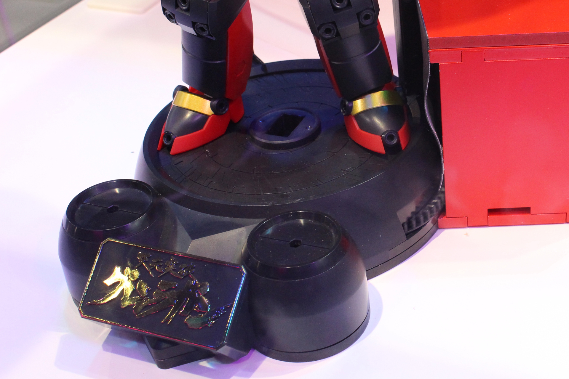 台座の向かって右側にあるギアを回すとドリルが回転。写真の赤い箱は展示用の電動ギミックで製品には付属せず、回転は手動で行う