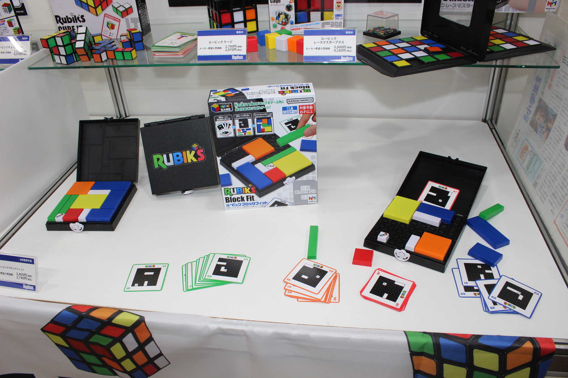 50周年に合わせて発売される新商品「ルービックブロックフィット」。カードのお題に則って白いブロックを最初に置き、残りのカラーブロックを全て収めるパズルだ