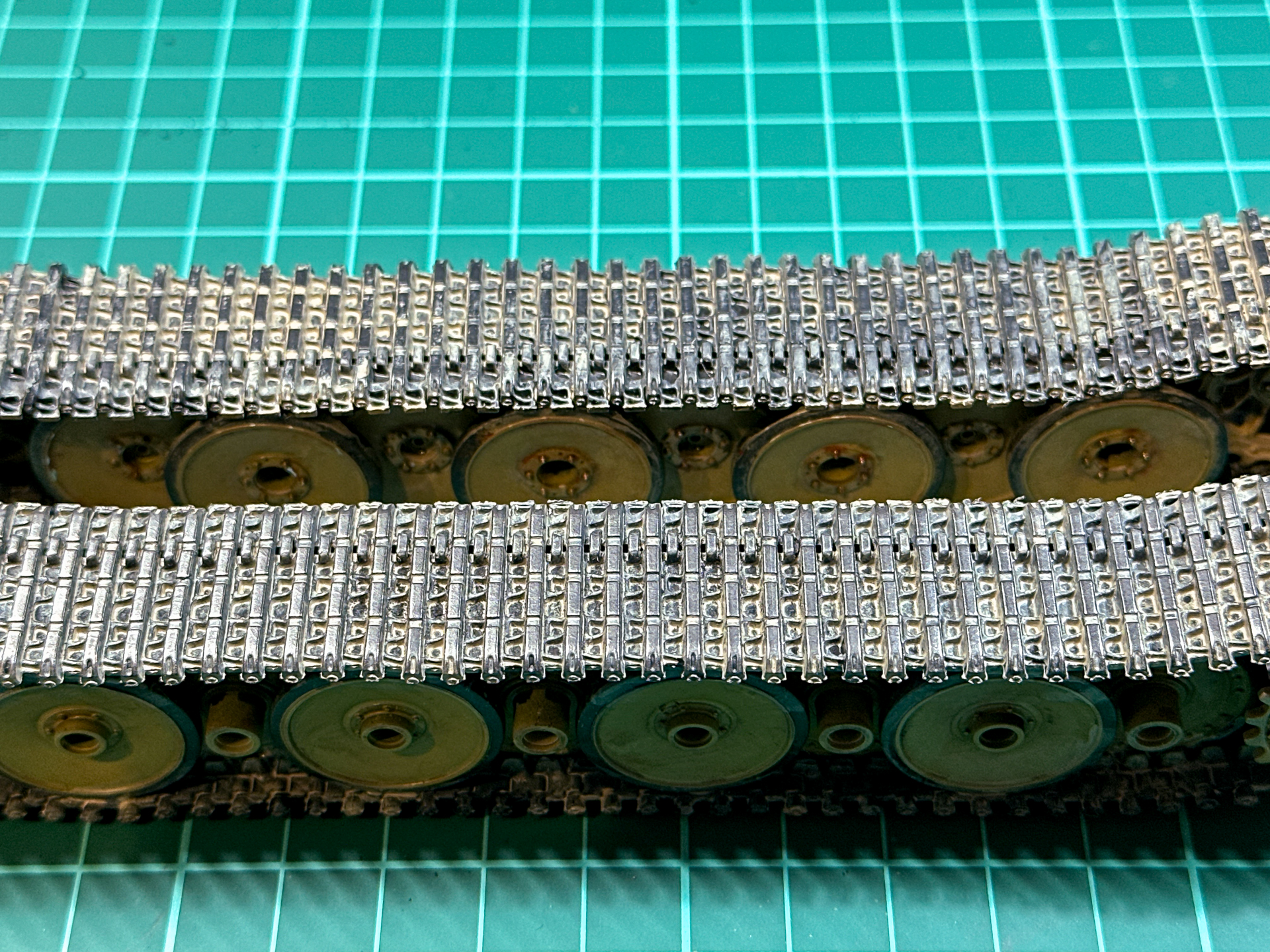 黒鉛塗布前（写真奥側）と黒鉛塗布後（写真手前側）の比較。履帯に独特の光沢が生まれました。