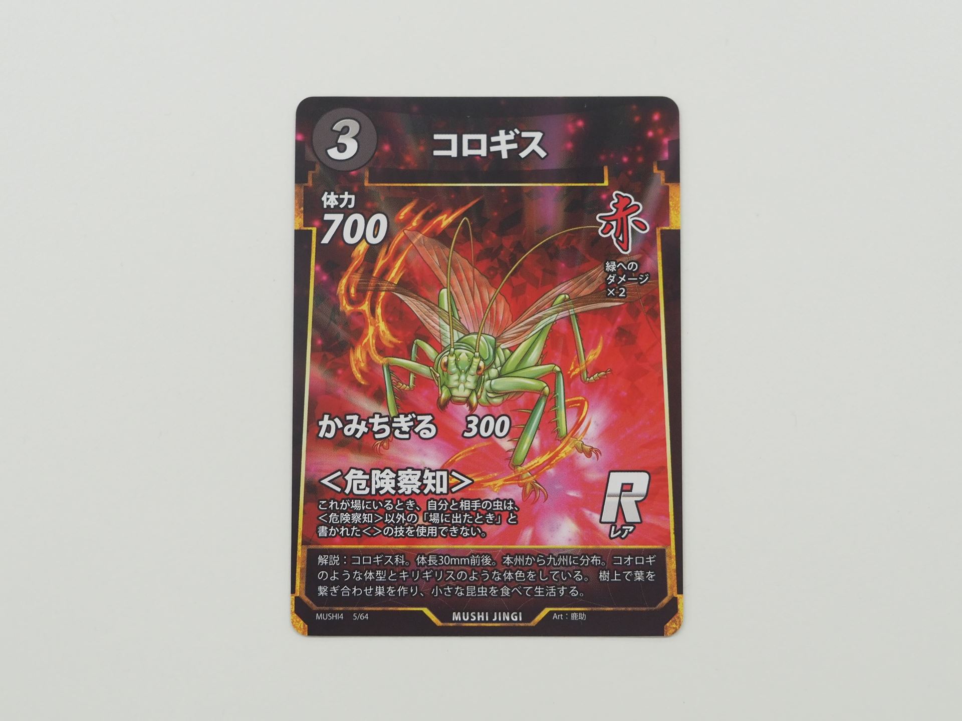 赤3コストのRカード「コロギス」。場にいるとき、自分と相手の虫は＜危険察知＞以外の場に出たときと書かれた＜＞技を使用できない＜危険察知＞を持つ
