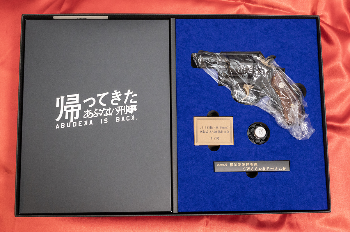 「『帰ってきたあぶない刑事』オフィシャルライセンスプロダクト 大下勇次モデル M10 2inch Early Heavy Weight DX」のボックスを開けたところ。銃と一緒に、カートリッジの箱が警察備品のようなデザインになっているのが雰囲気アップだ
