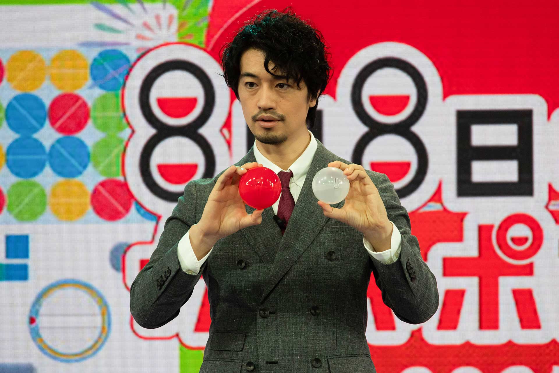 「90mm カプセル」と従来までの「79mm カプセル」を手に持って比べる斎藤さん