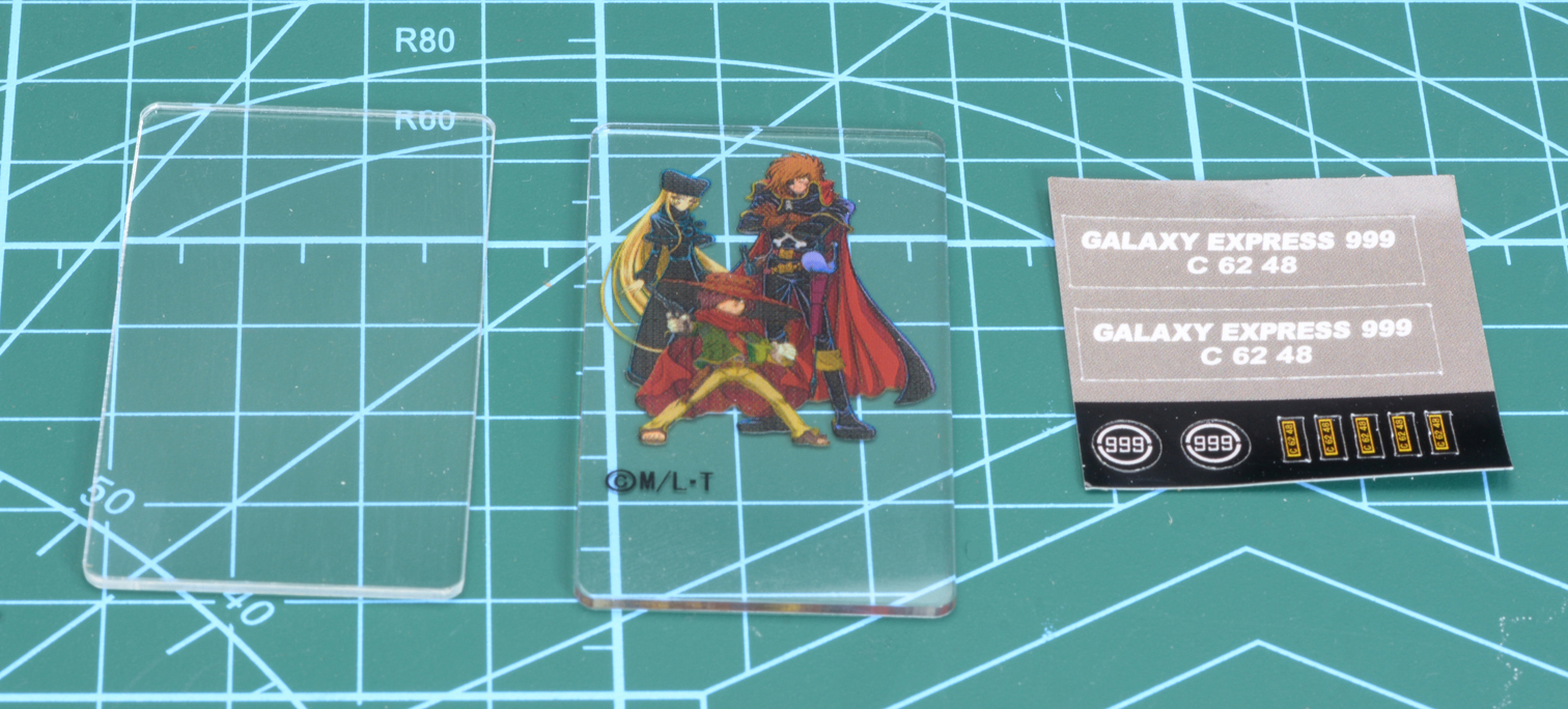 アクリル板とシール。アクリル板には鉄郎、メーテル、ハーロックが印刷されている