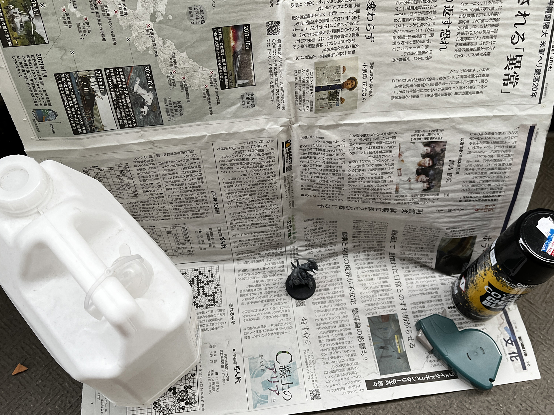 筆者は新聞紙をマスキングテープでベランダの壁に貼ってスプレーを吹いている。左脇に置かれているのは重し用のタンク。スプレーを吹いた後の新聞紙は燃えるごみへ