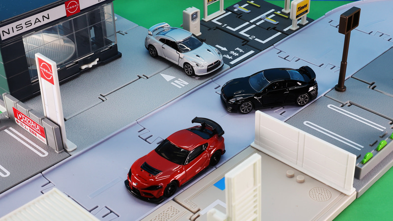 「No.22 GR スープラ GT4 EVO」通常仕様（手前：オレンジ）、「トミカプレミアム 17 日産 NISSAN GT-R」通常仕様（奥：シルバー）・発売記念仕様（右：ブラック）