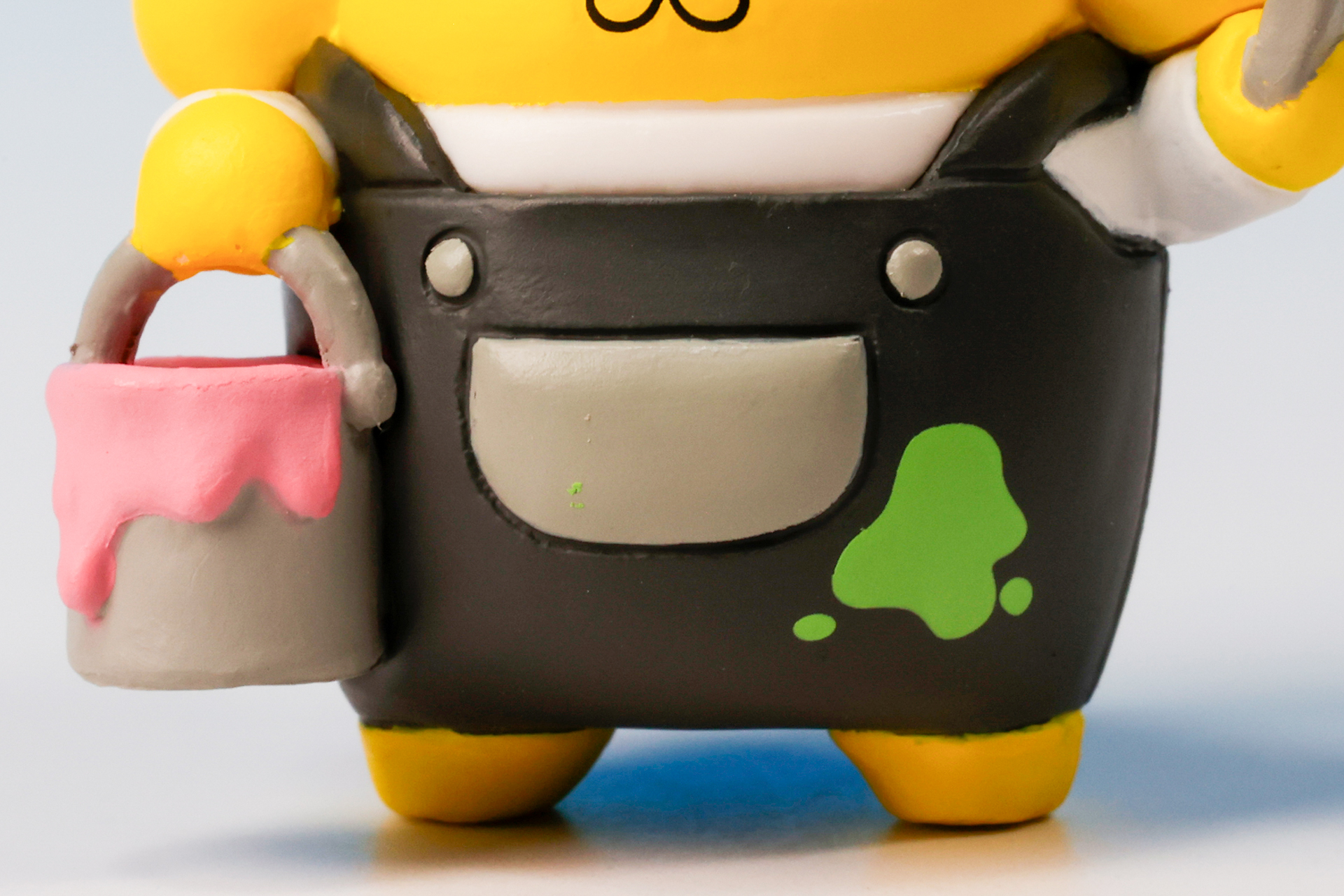 ポムポムプリンが持っているのはピンク色のペンキだが、服には緑色のペンキが付いている