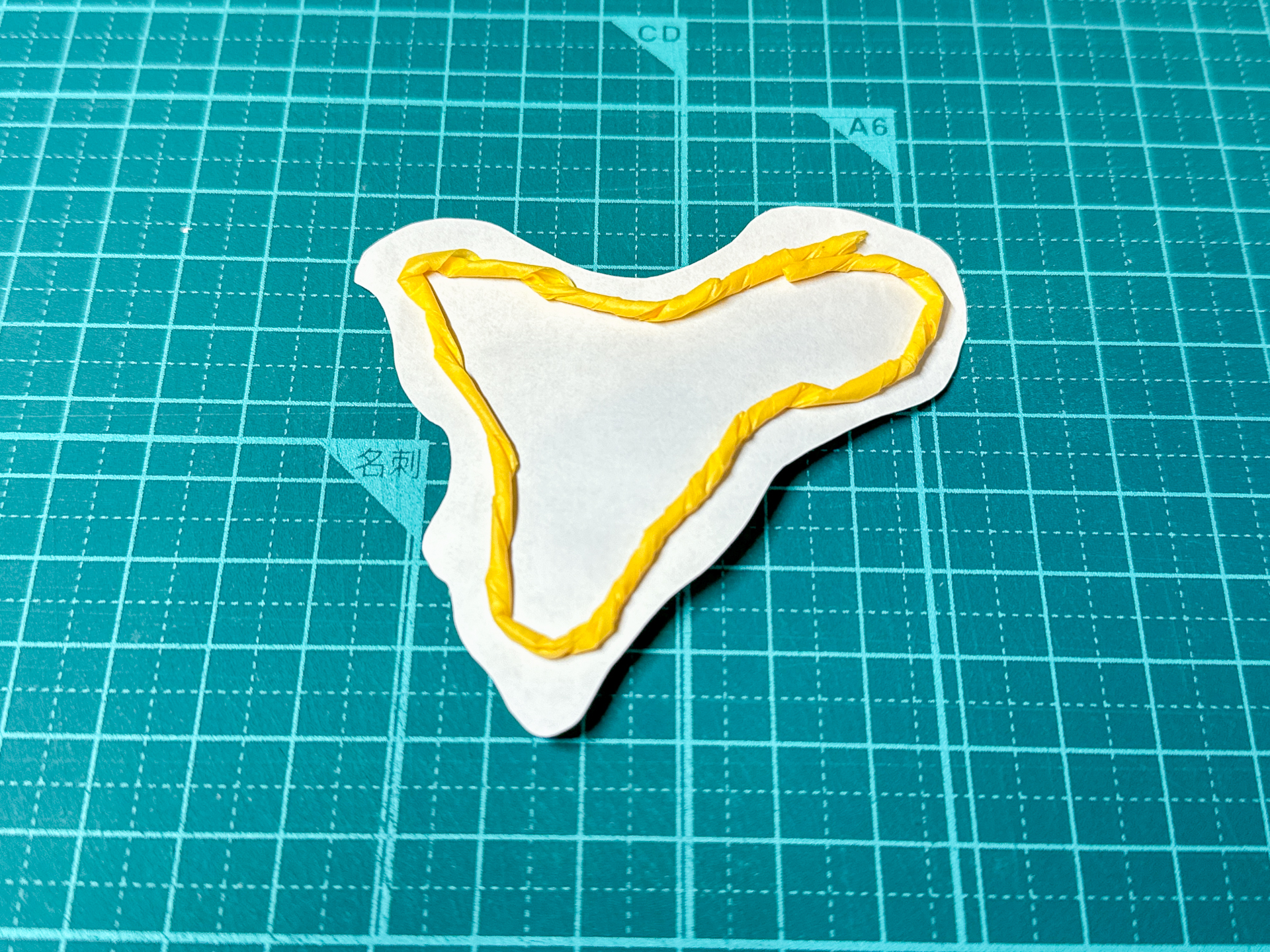 切り抜いた型紙の裏側にこより状にしたマスキングテープを貼り付けます。