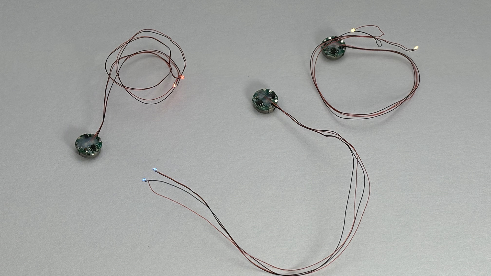 ビット・トレード・ワンの「磁気スイッチ付LEDモジュールリード線仕様」。20cmのリード線が2本。基盤は直径約11mm、高さ約5mmの小ささで、プラモデルにも簡単に組み込める。2灯式は1つの基板から2組のリード線が伸びている。